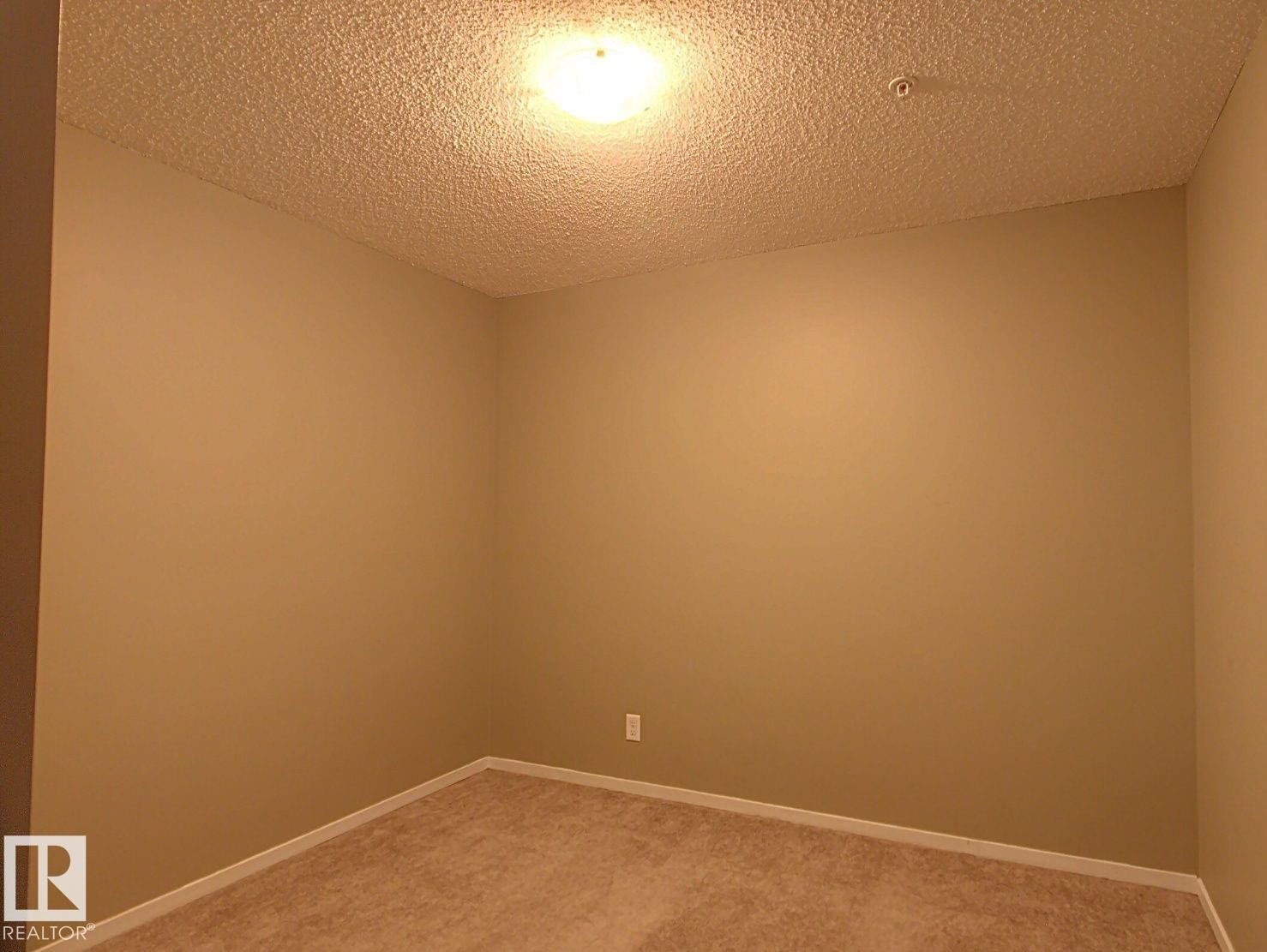 Room with tan wall paint and textured ceiling, featuring recessed lighting and carpet flooring - 328 3315 James Mowatt Trail, Edmonton, AB