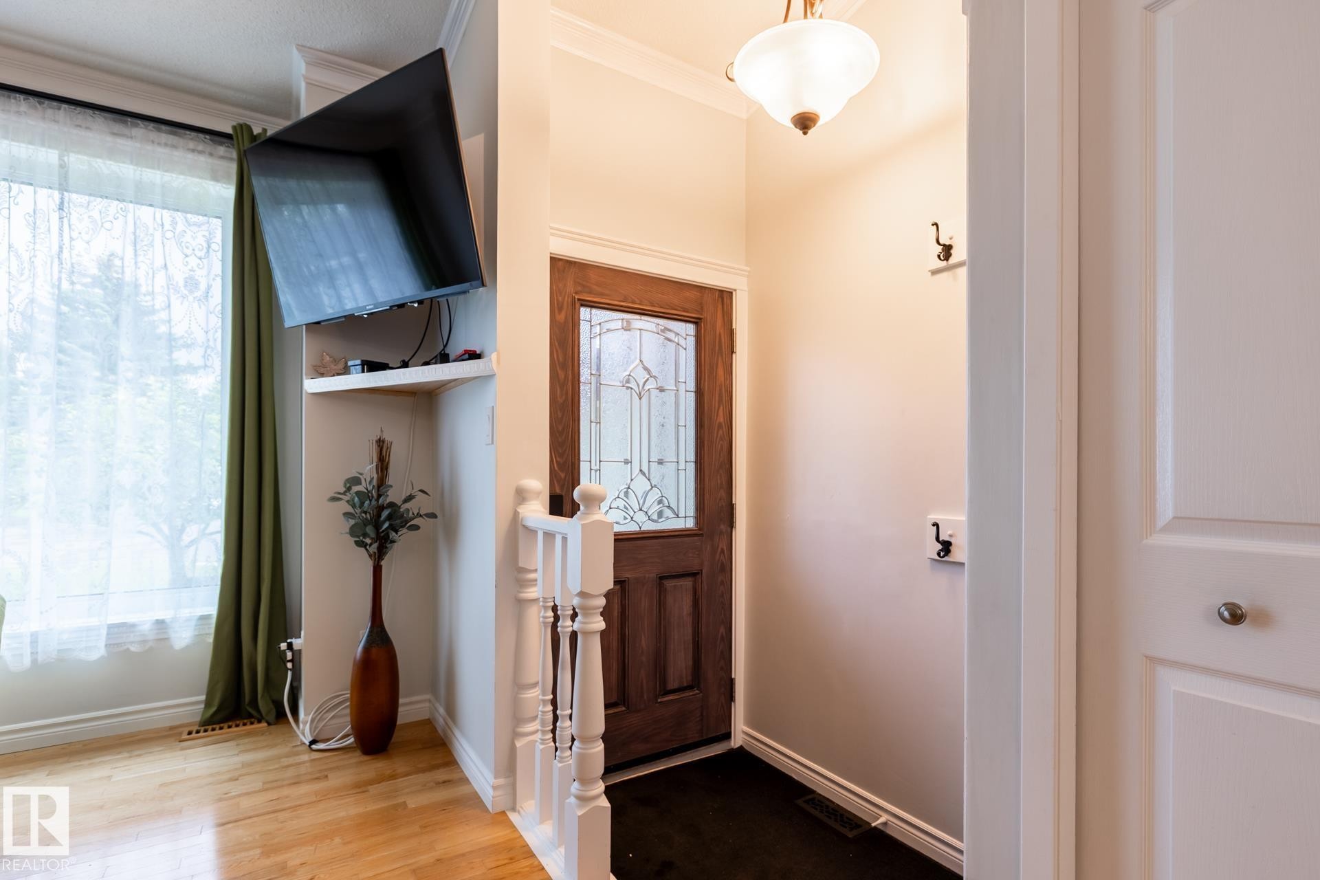 Entryway featuring a wood-finish door with leaded glass, white trim, and a ceiling-mounted light fixture - 27 Danforth Crescent, St. Albert, AB