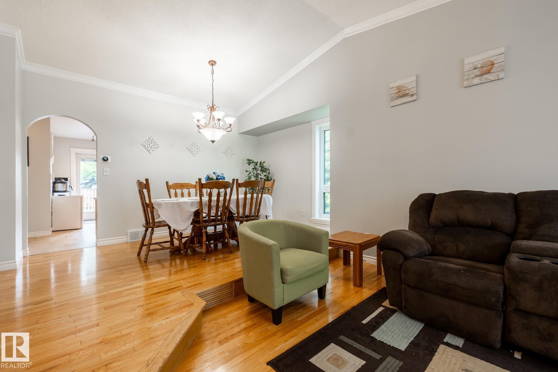 Spacious interior featuring wood-finish flooring, vaulted ceilings, and an arched doorway - 27 Danforth Crescent, St. Albert, AB