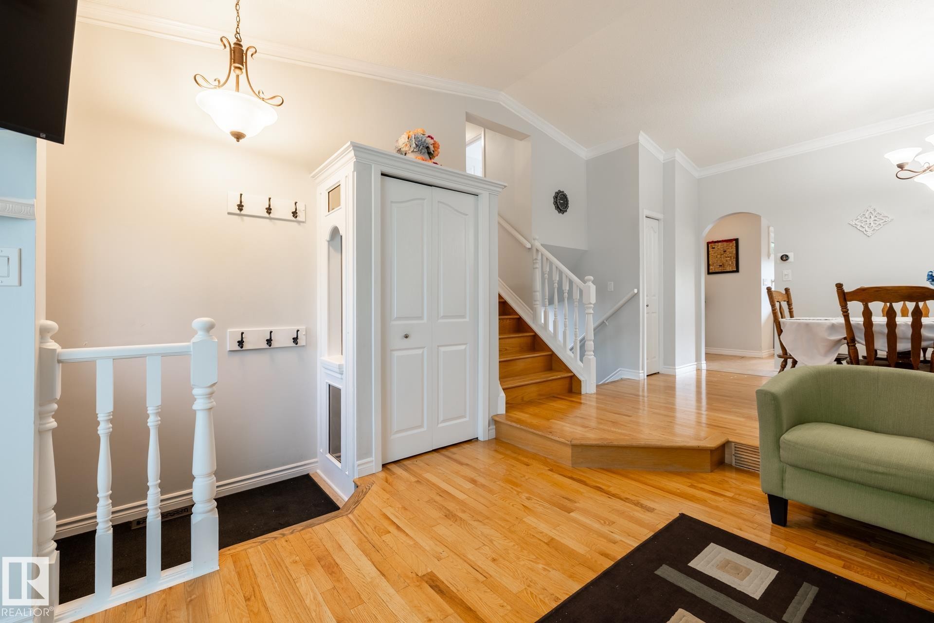 Entryway featuring wood-finish flooring, white baluster railing, and a built-in closet with bifold doors - 27 Danforth Crescent, St. Albert, AB