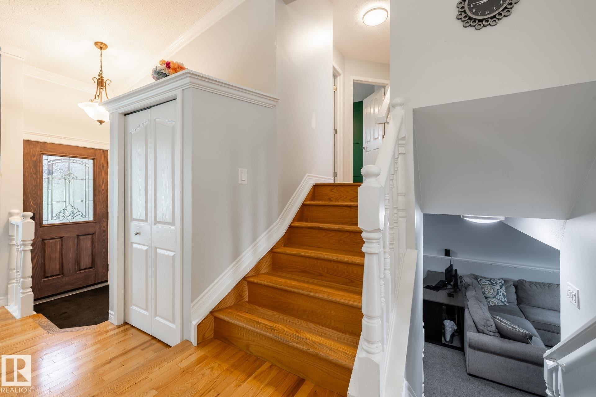 Entryway featuring natural wood-finish flooring, a leaded glass front door, and a traditional chandelier - 27 Danforth Crescent, St. Albert, AB