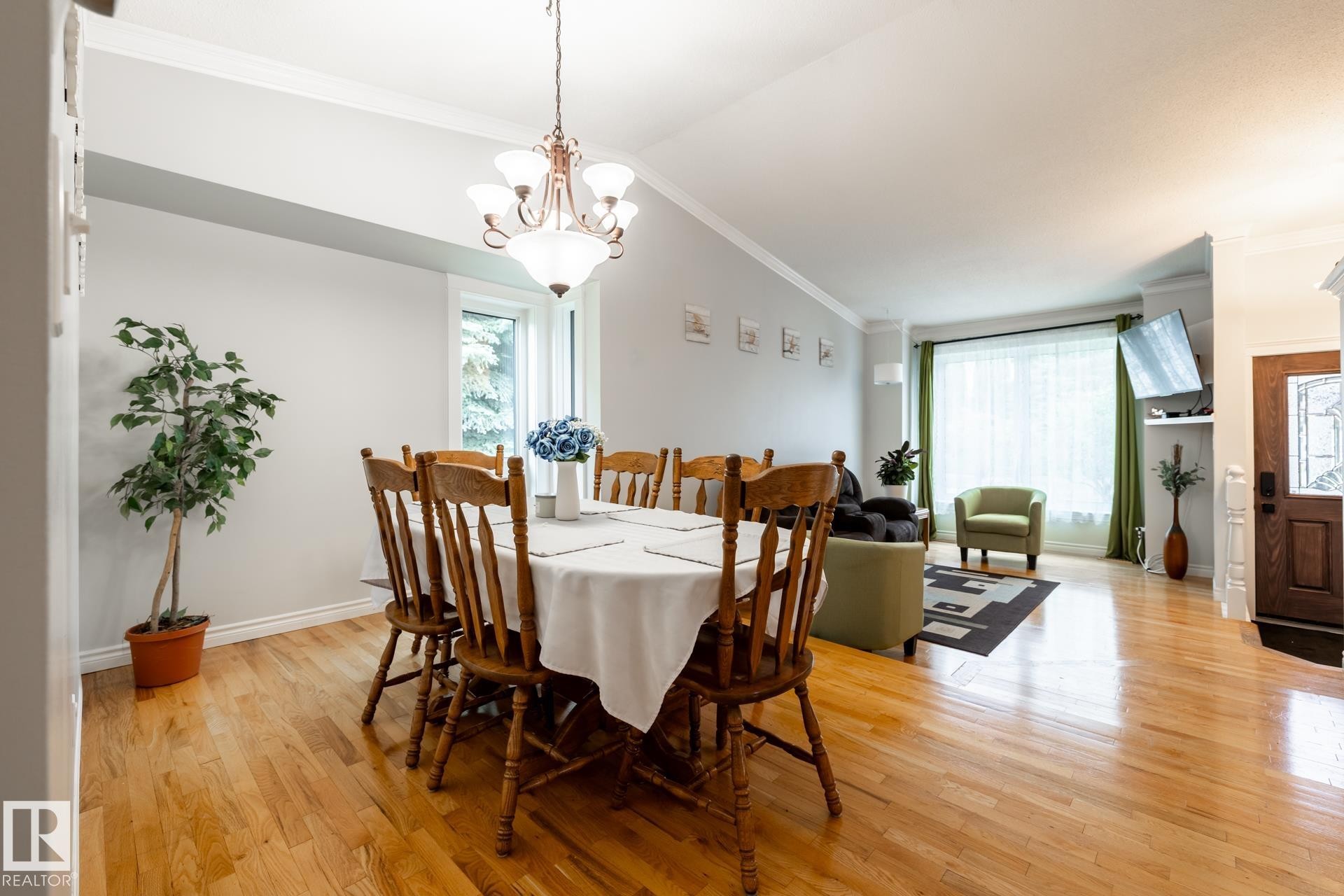 Bright dining area featuring hardwood flooring, crown molding, and a prominent chandelier - 27 Danforth Crescent, St. Albert, AB
