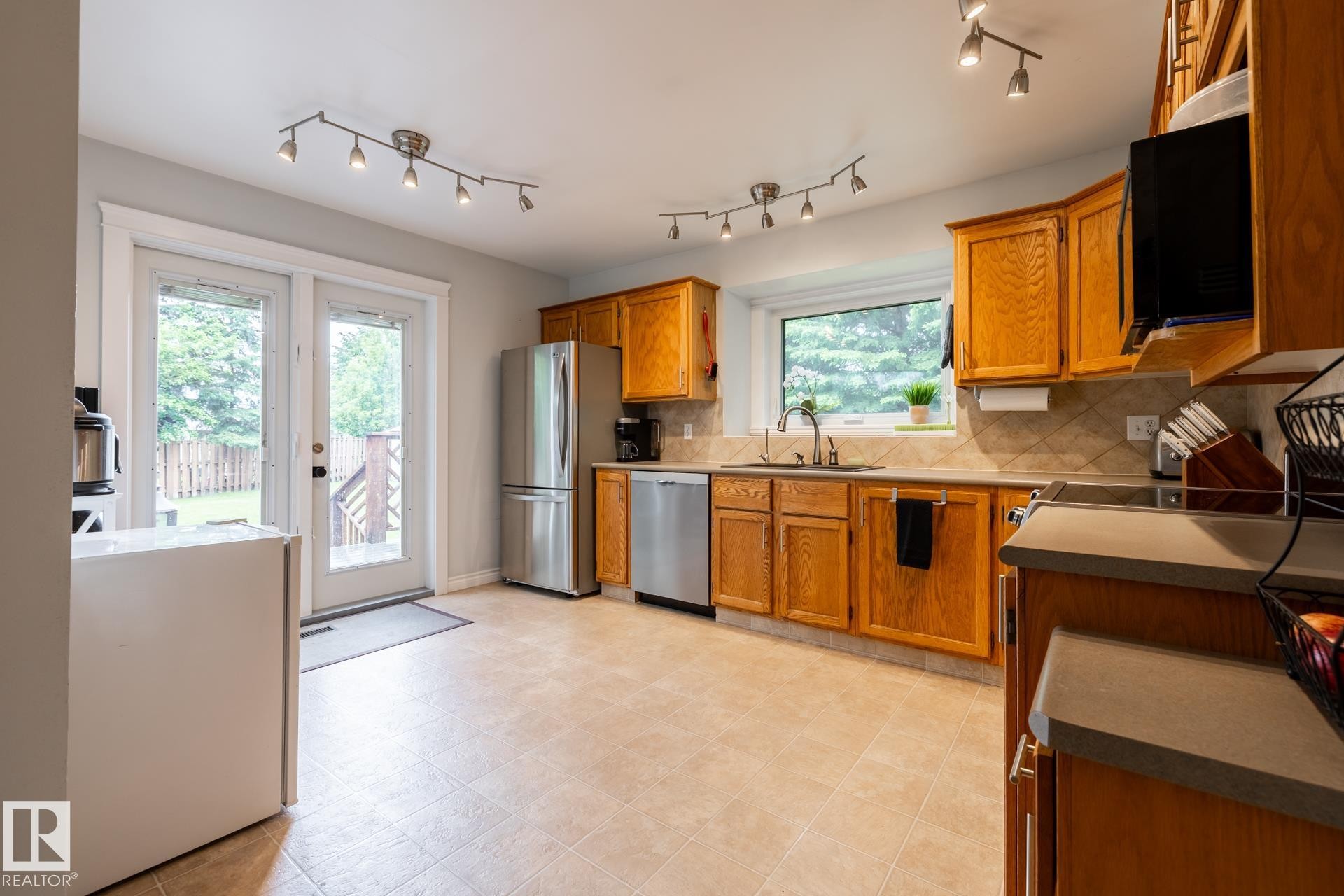 Kitchen featuring light wood cabinetry, stainless steel appliances, and track lighting - 27 Danforth Crescent, St. Albert, AB