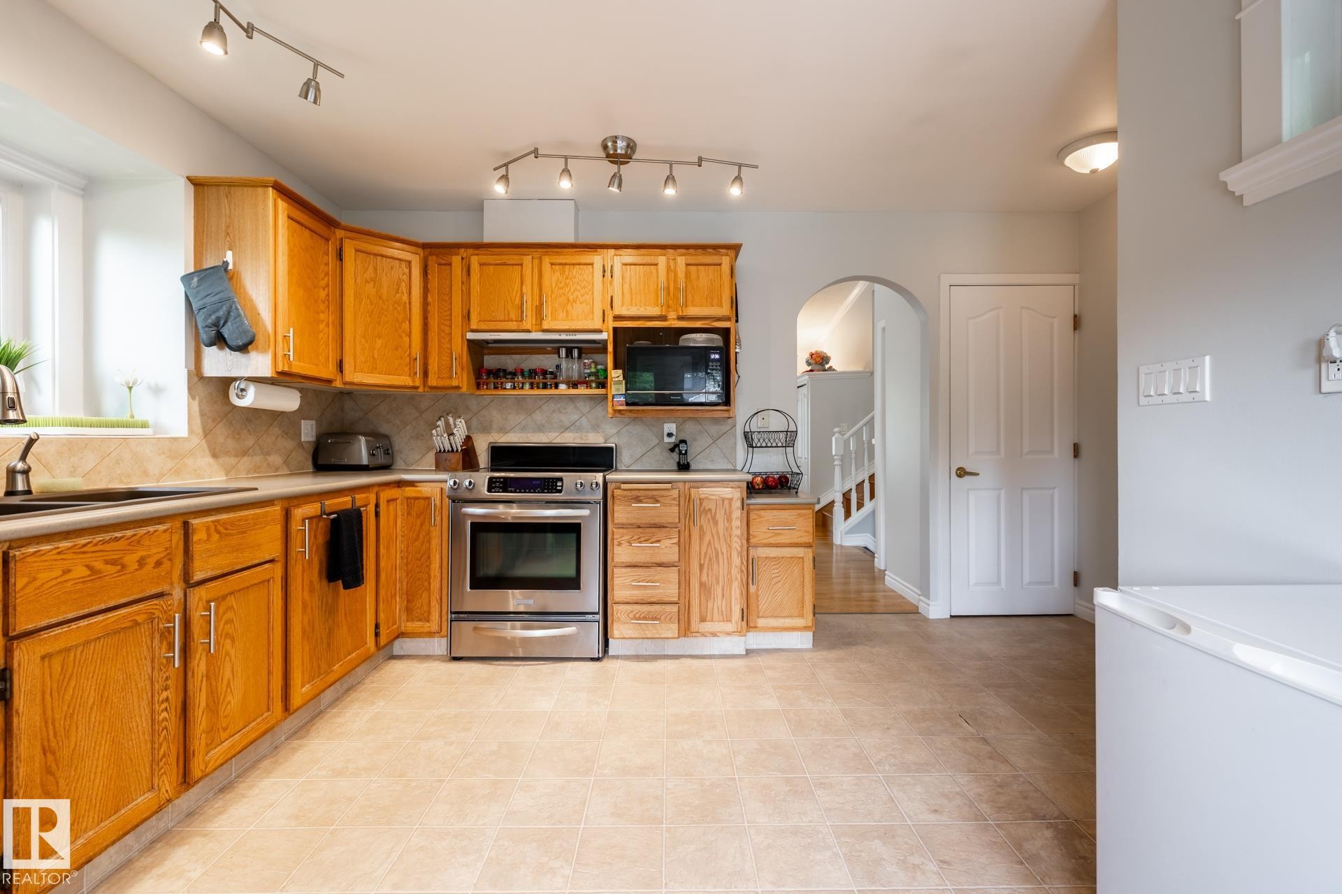 Kitchen featuring wood cabinetry, stainless steel range, and tile flooring - 27 Danforth Crescent, St. Albert, AB