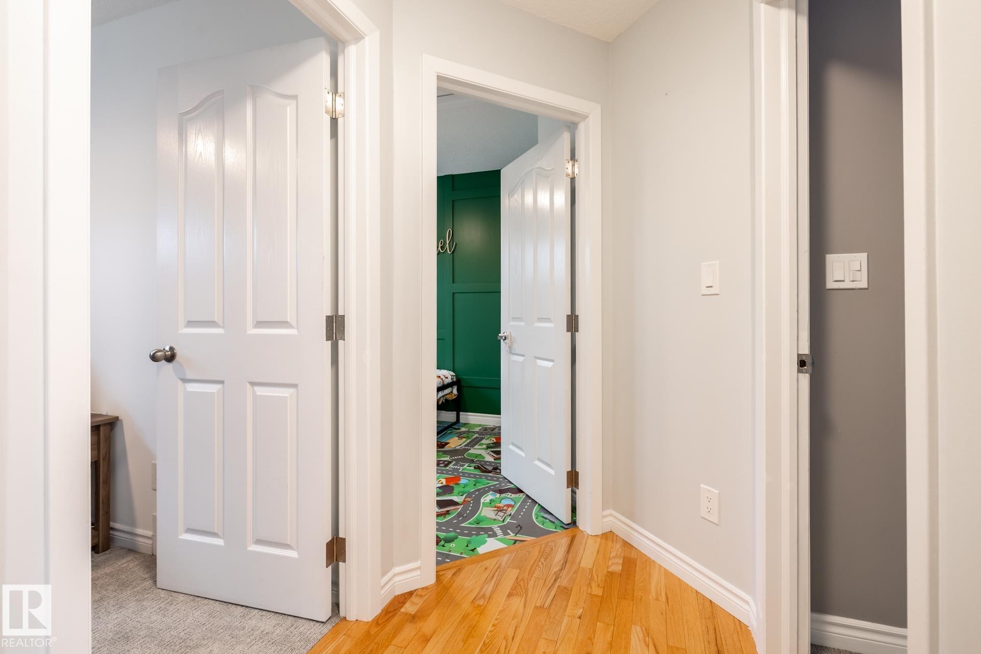 Hallway featuring light-toned walls, wood-finish flooring, and white trim - 27 Danforth Crescent, St. Albert, AB