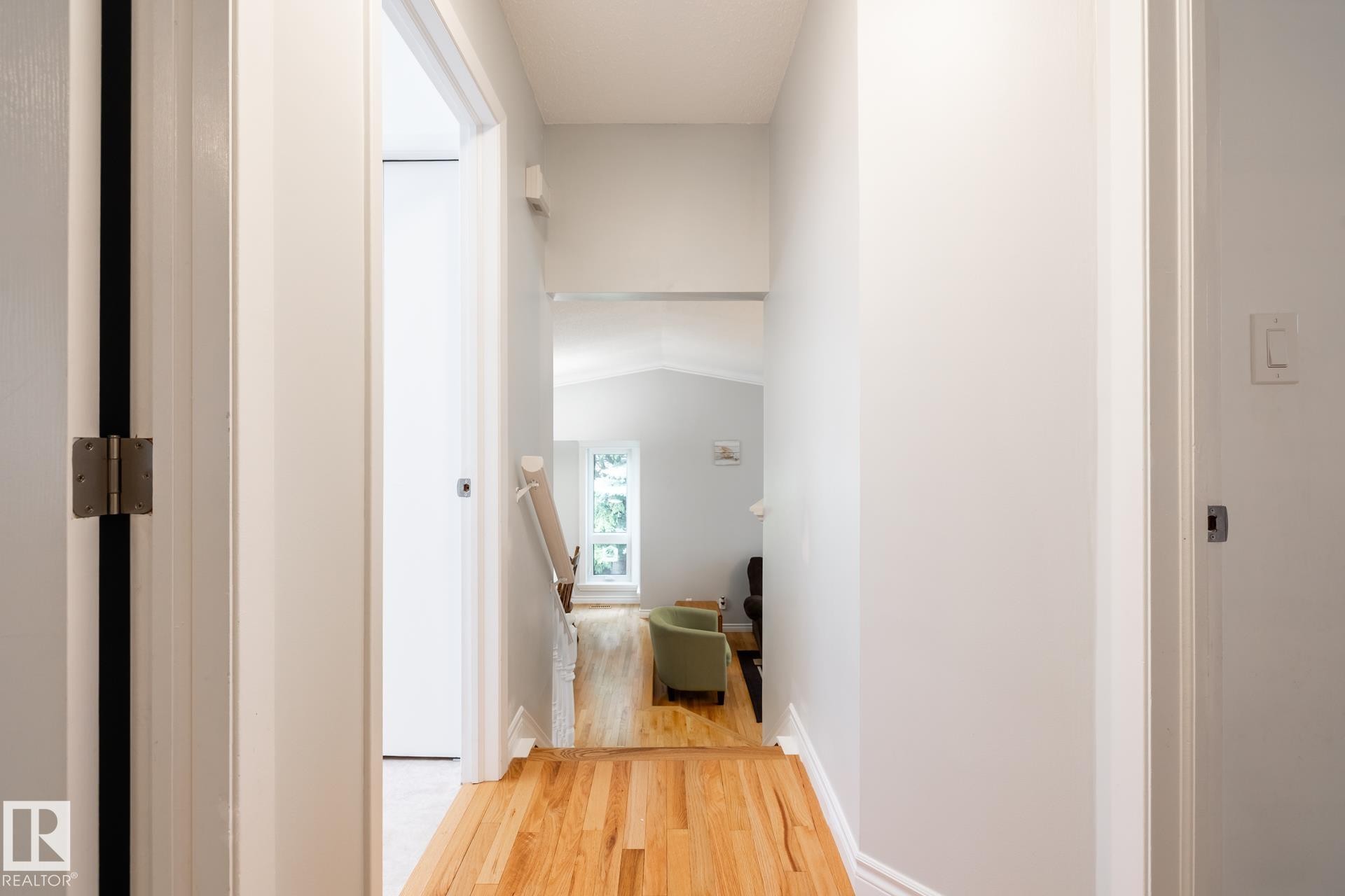 Hallway with wood-finish flooring, light-toned walls, and white trim - 27 Danforth Crescent, St. Albert, AB