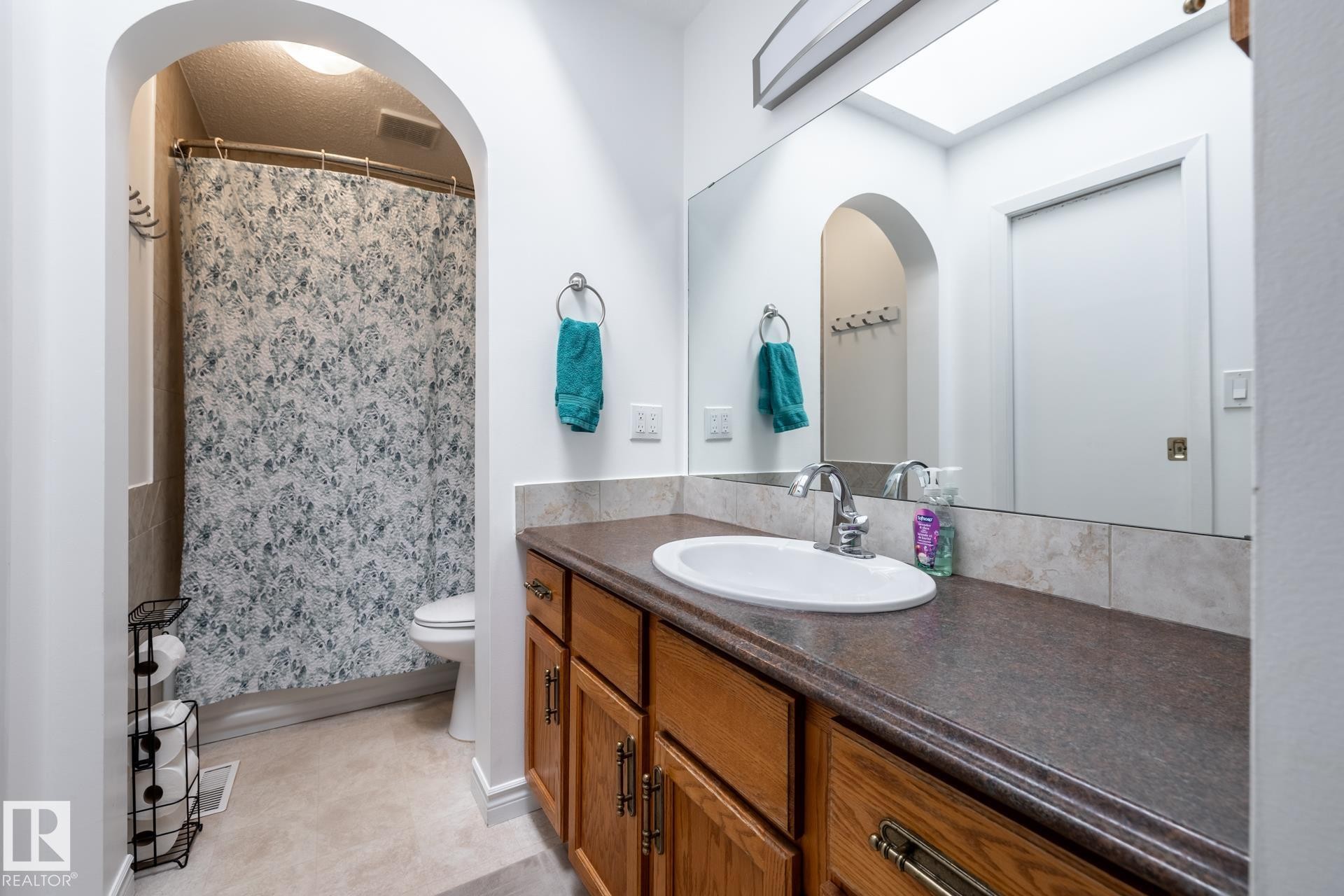 Bathroom featuring a vanity with an integrated sink, laminate countertop, and wood cabinetry - 27 Danforth Crescent, St. Albert, AB