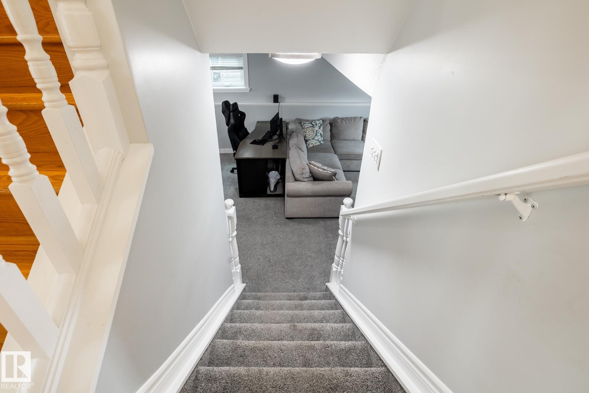 Carpeted stairs with white wooden railings descend to a lower level featuring light gray walls, a window, and recessed ceiling lighting - 27 Danforth Crescent, St. Albert, AB