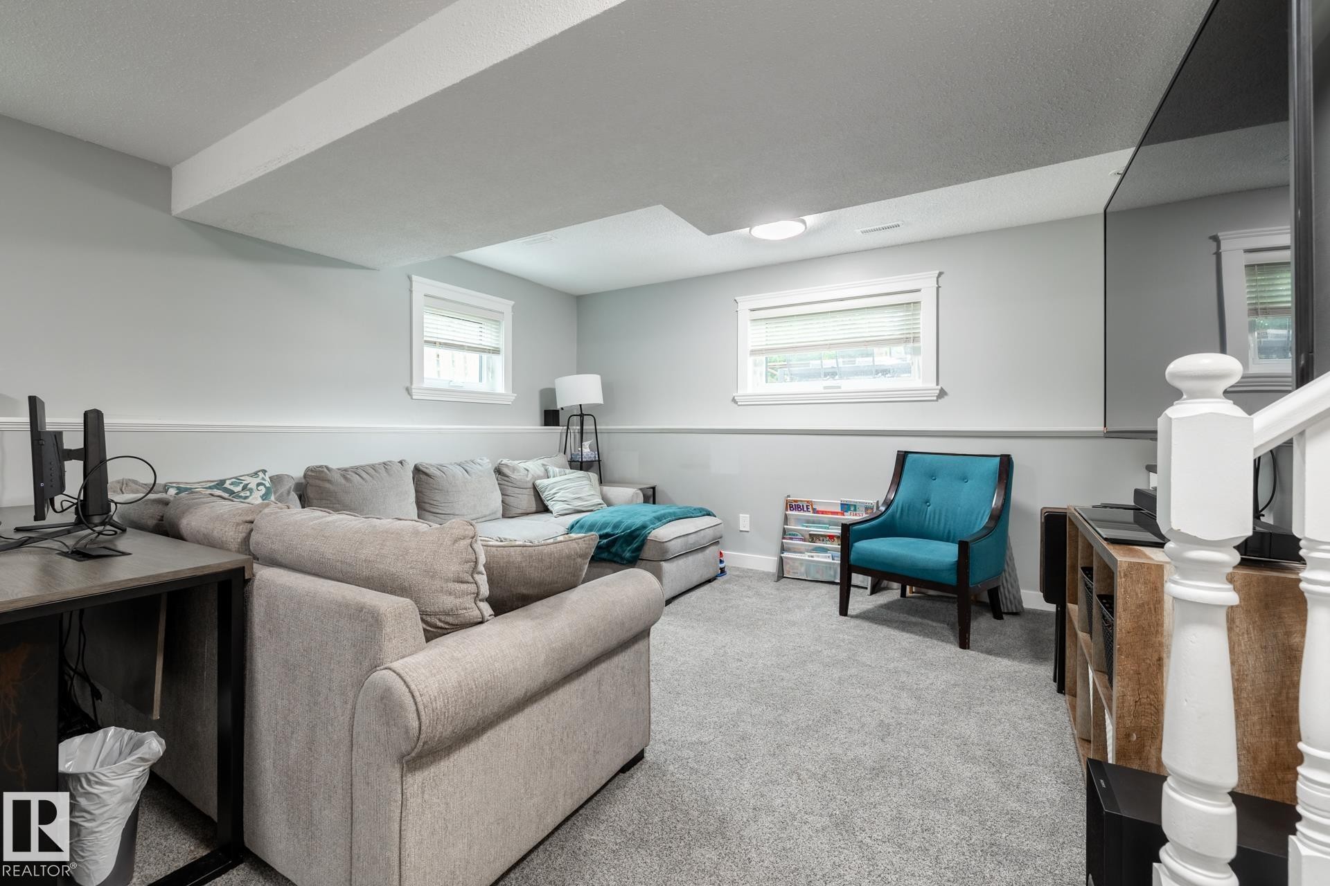 Carpeted recreation room featuring white trim, two windows, recessed lighting, and a built-in media console - 27 Danforth Crescent, St. Albert, AB