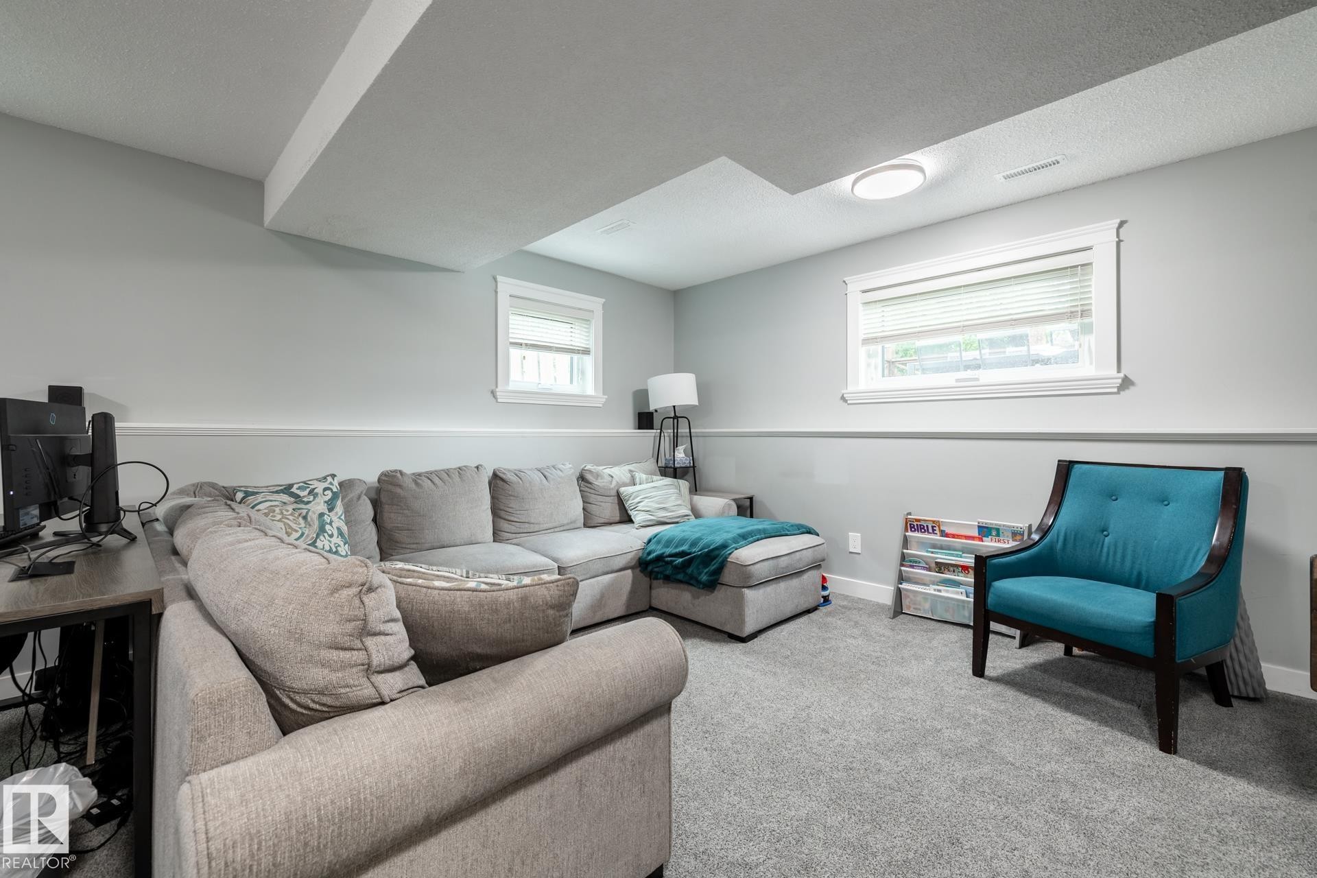 Carpeted room featuring two windows with white trim, a flush-mount ceiling light, and chair rail molding - 27 Danforth Crescent, St. Albert, AB