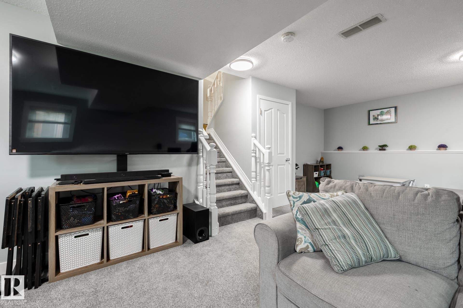 Finished living area featuring light gray walls and plush gray carpeting - 27 Danforth Crescent, St. Albert, AB