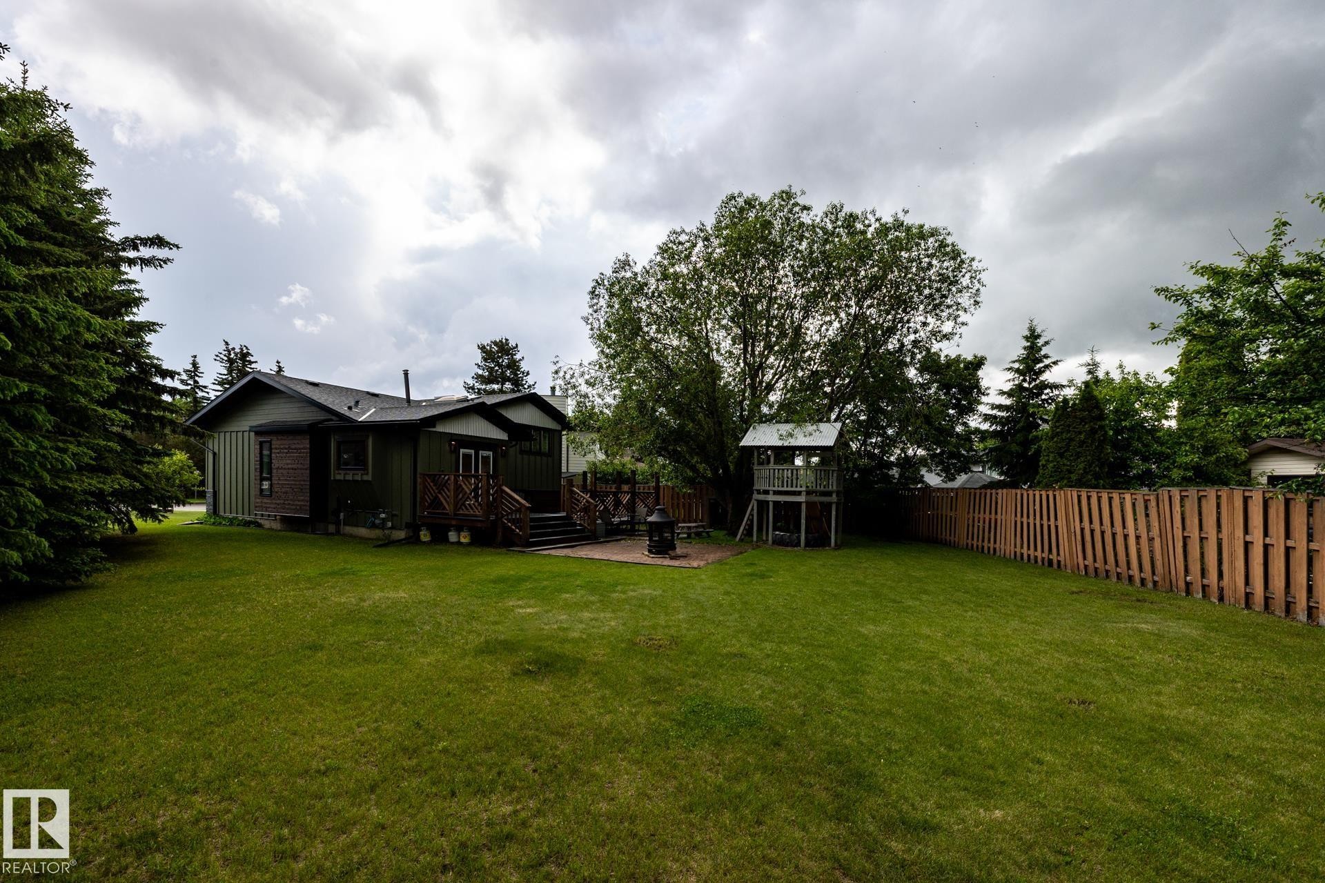 Spacious rear yard featuring extensive lawn area, mature trees, and a full privacy fence - 27 Danforth Crescent, St. Albert, AB