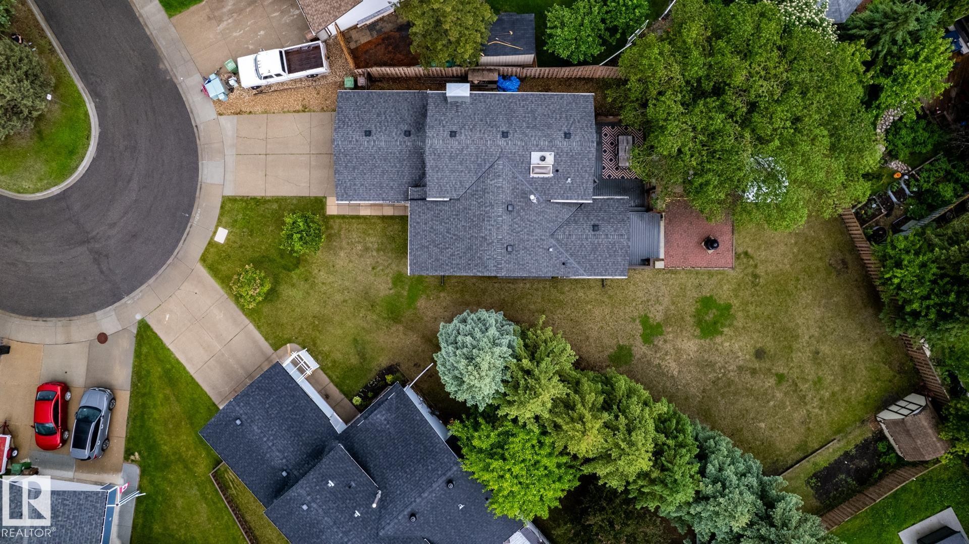 Residence featuring a dark shingle roof, expansive backyard, mature trees, and a concrete driveway - 27 Danforth Crescent, St. Albert, AB