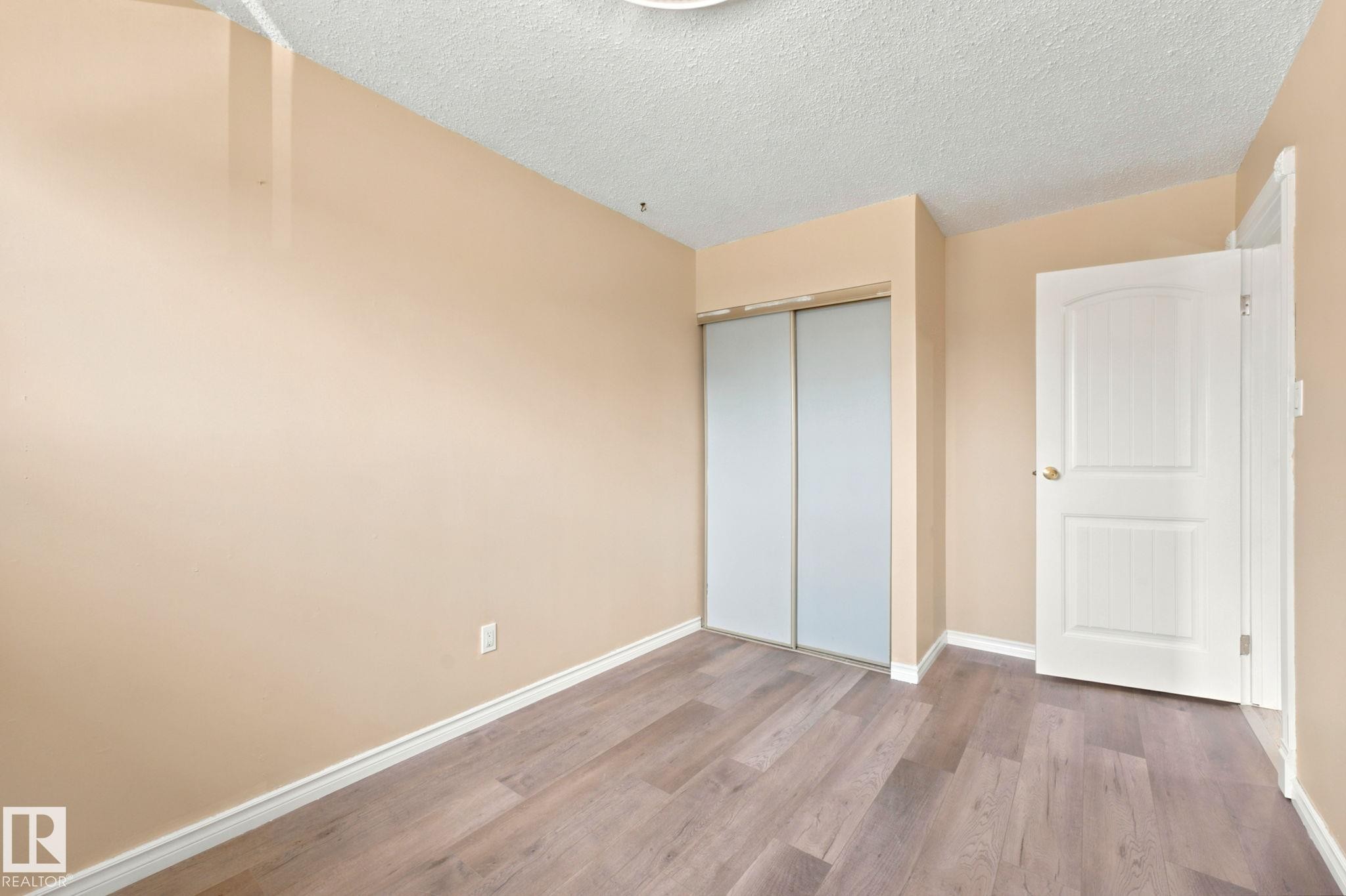Interior room featuring wood-finish flooring, light beige walls, and white baseboards - #41 4707 126 Av Nw, Edmonton, AB