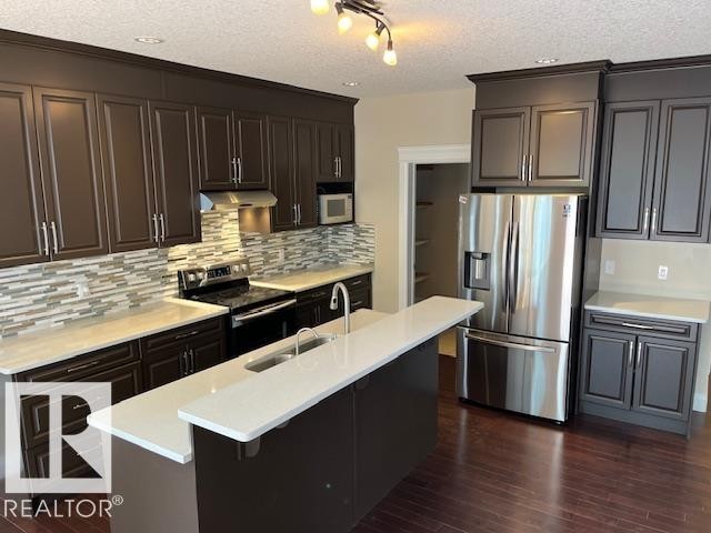 Modern kitchen featuring rich cabinetry, light countertops, and a full suite of stainless steel appliances - 805 Hodgins Road, Edmonton, AB