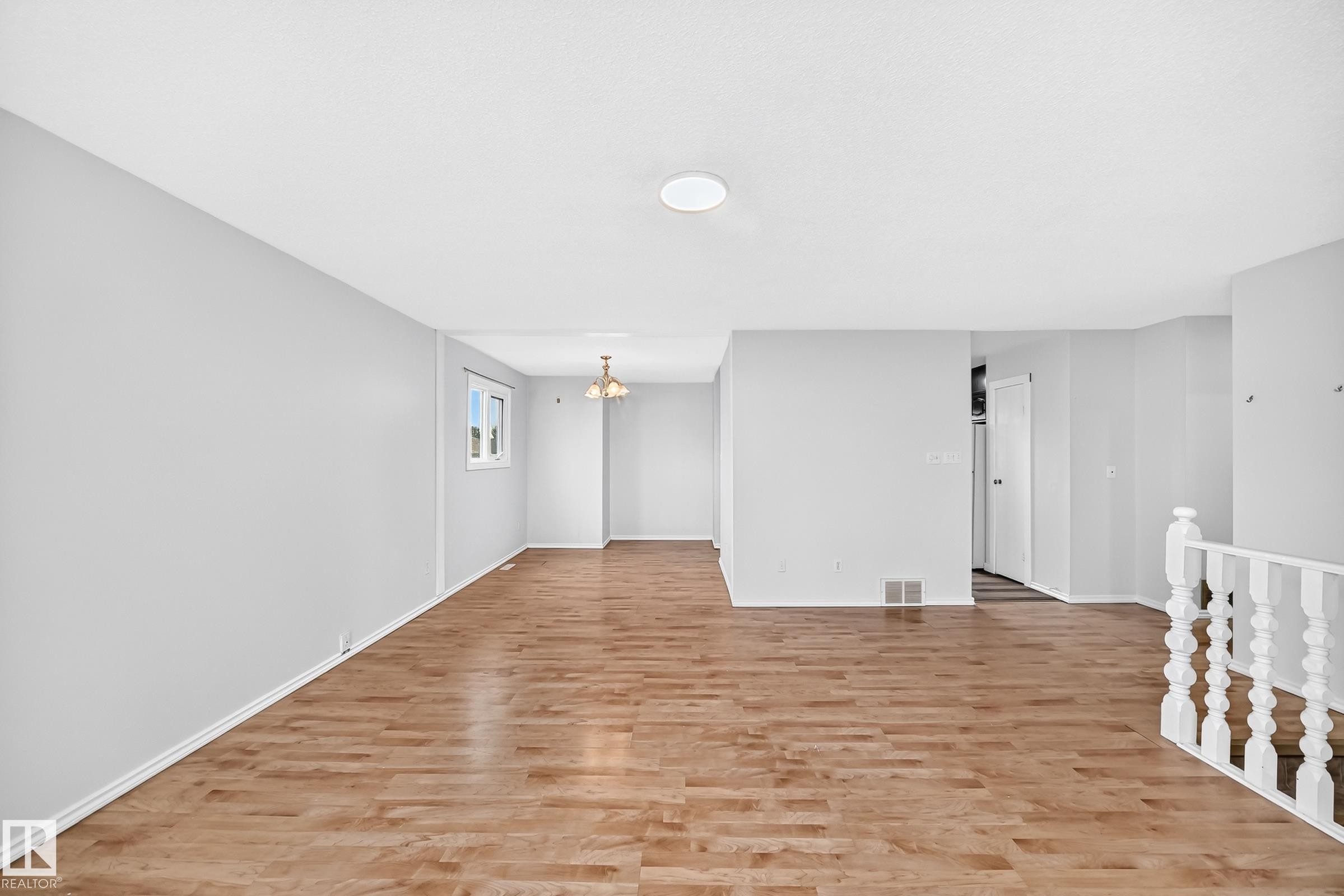 Expansive interior space featuring wood-finish flooring, light gray walls, and white trim - 1103 56 Street, Edmonton, AB