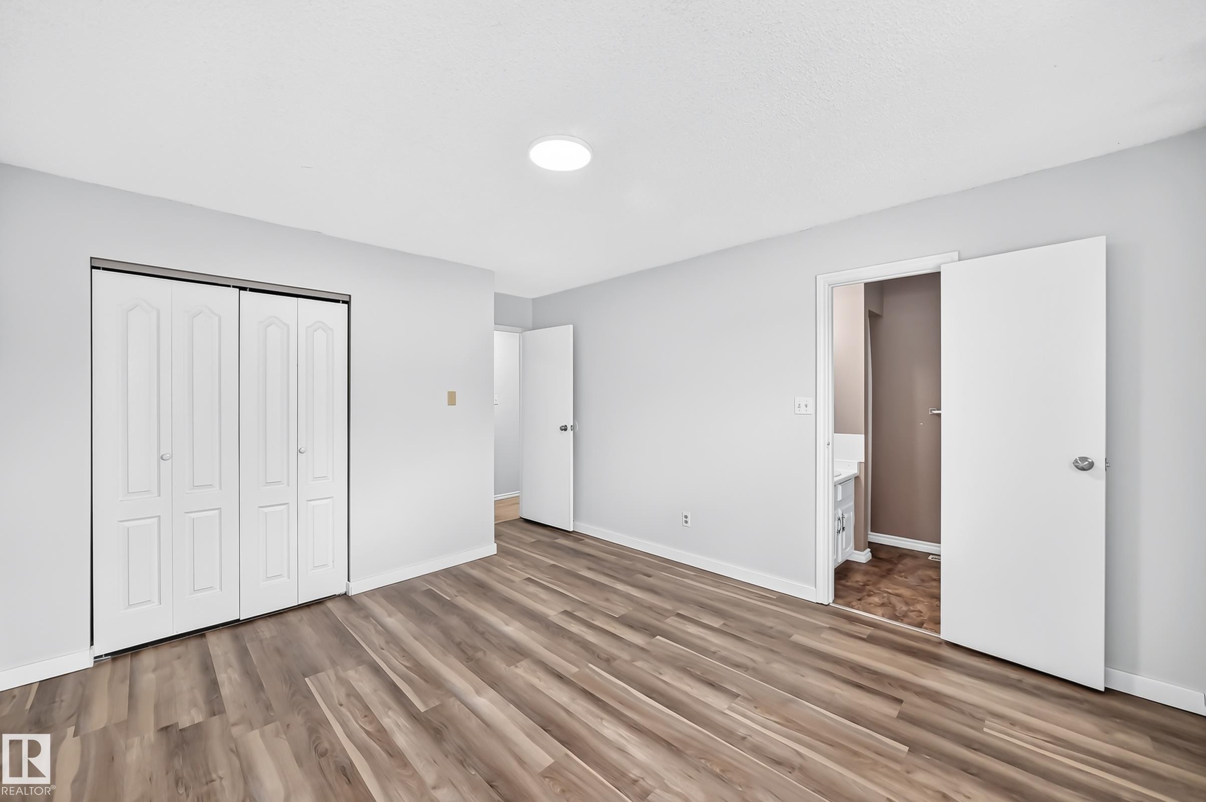 Spacious room featuring wood-finish flooring, light grey walls, and a recessed ceiling light - 1103 56 Street, Edmonton, AB