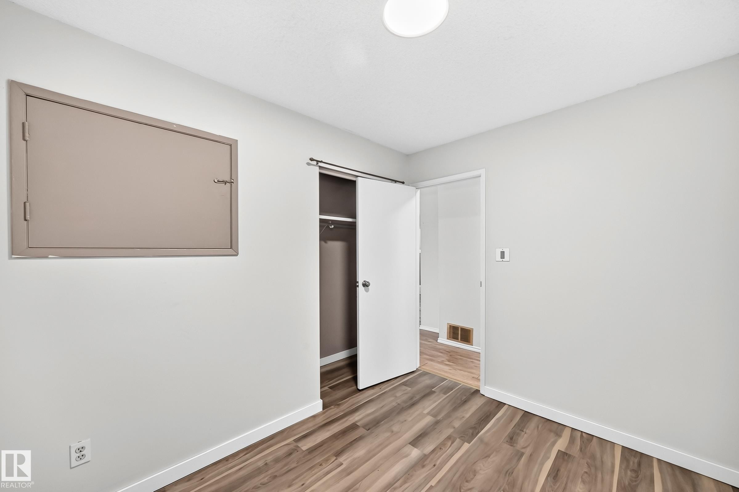 Room featuring wood-finish flooring, light grey painted walls, and white baseboards - 1103 56 Street, Edmonton, AB