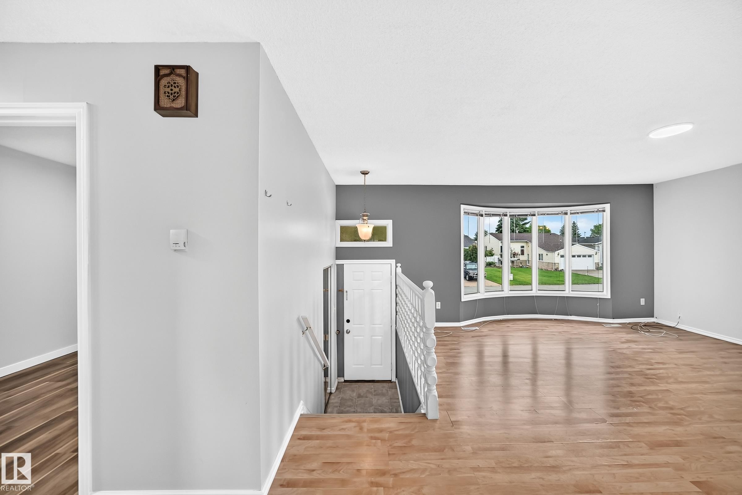 Inviting entryway featuring a white door with transom window, complemented by a white handrail and light wood-finish flooring - 1103 56 Street, Edmonton, AB