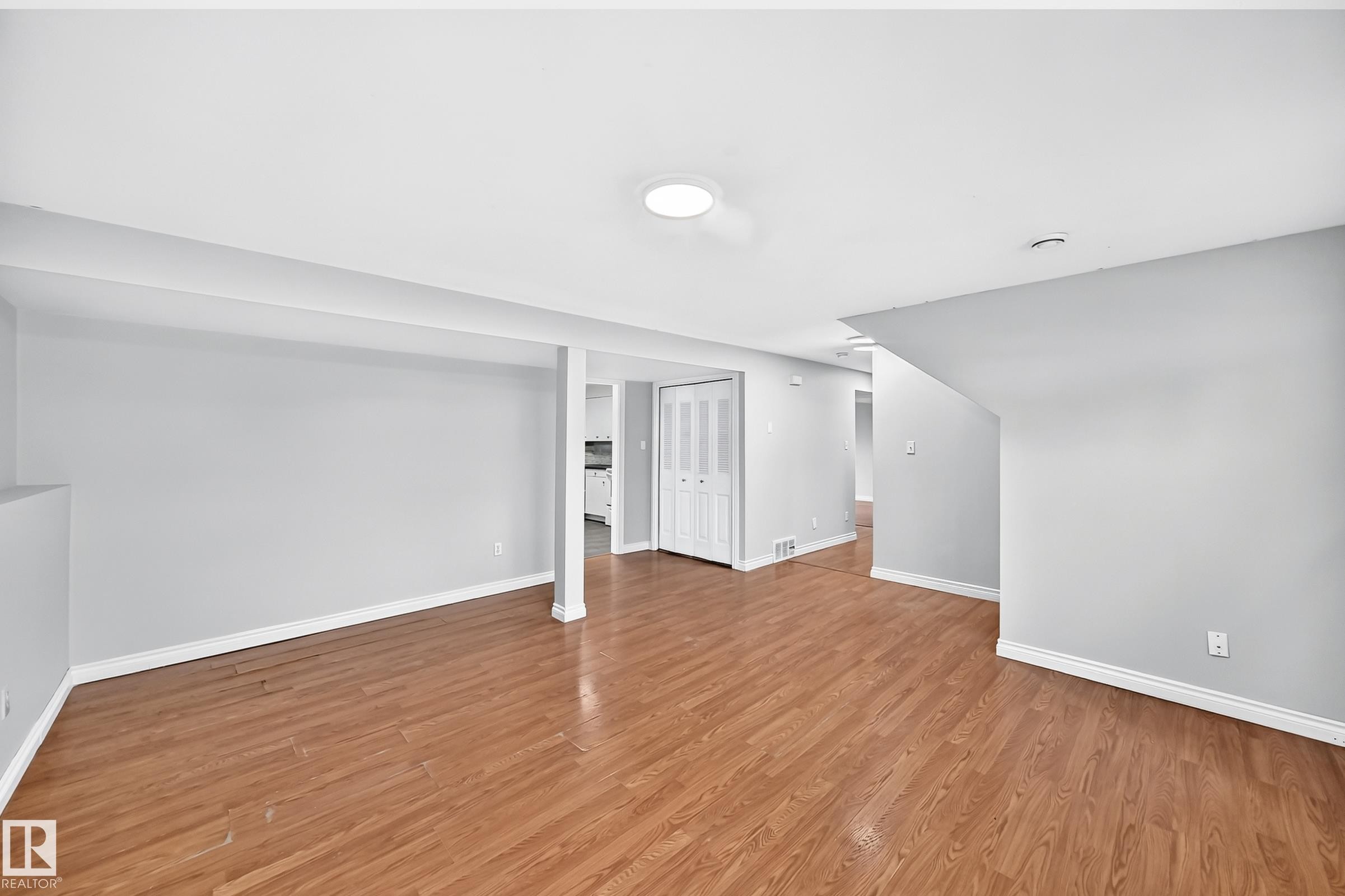 Open-concept living area with wood-finish flooring, recessed lighting, and light gray wall tones - 1103 56 Street, Edmonton, AB