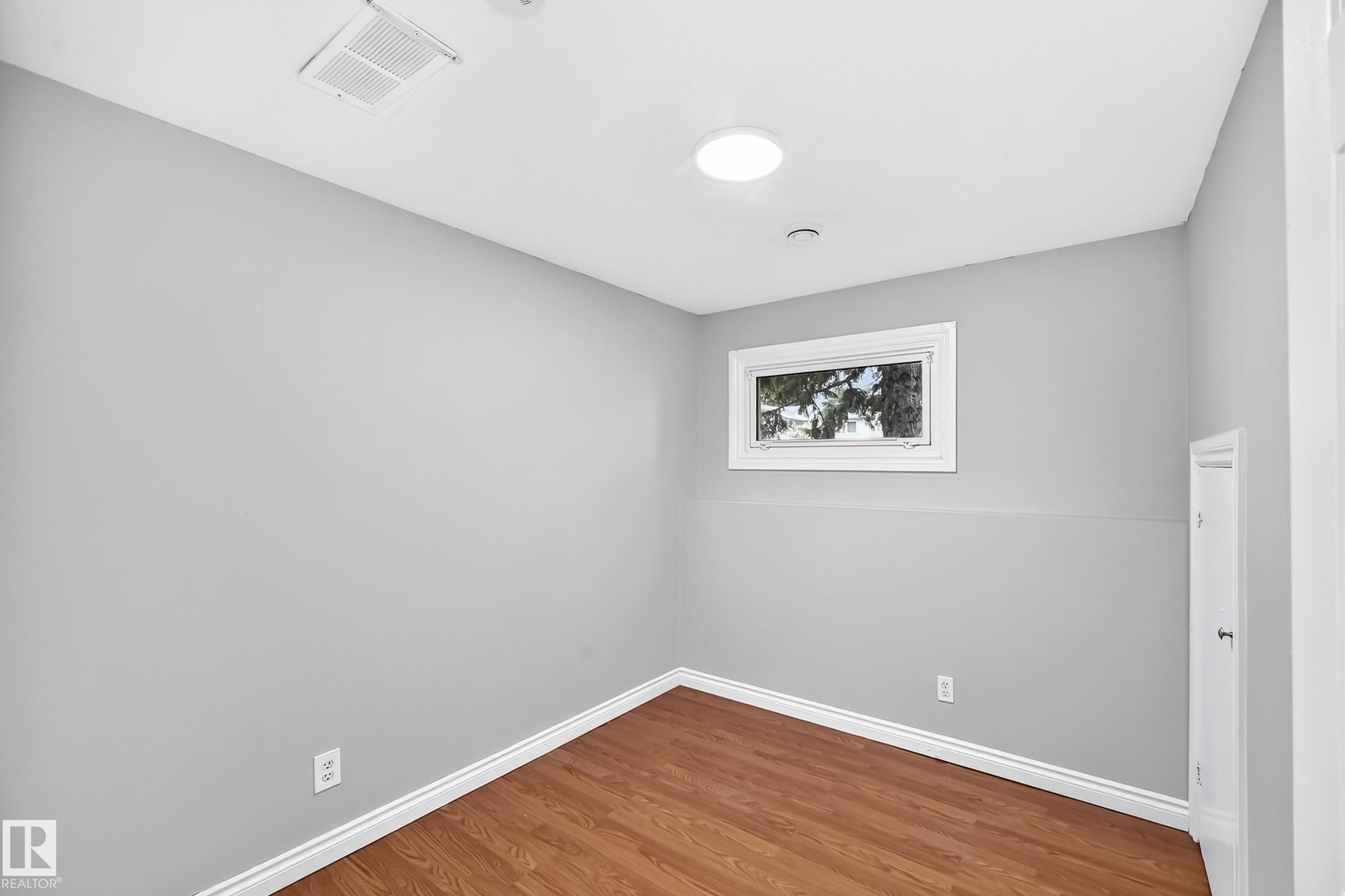Room featuring wood-finish flooring, light gray walls, and white baseboards - 1103 56 Street, Edmonton, AB