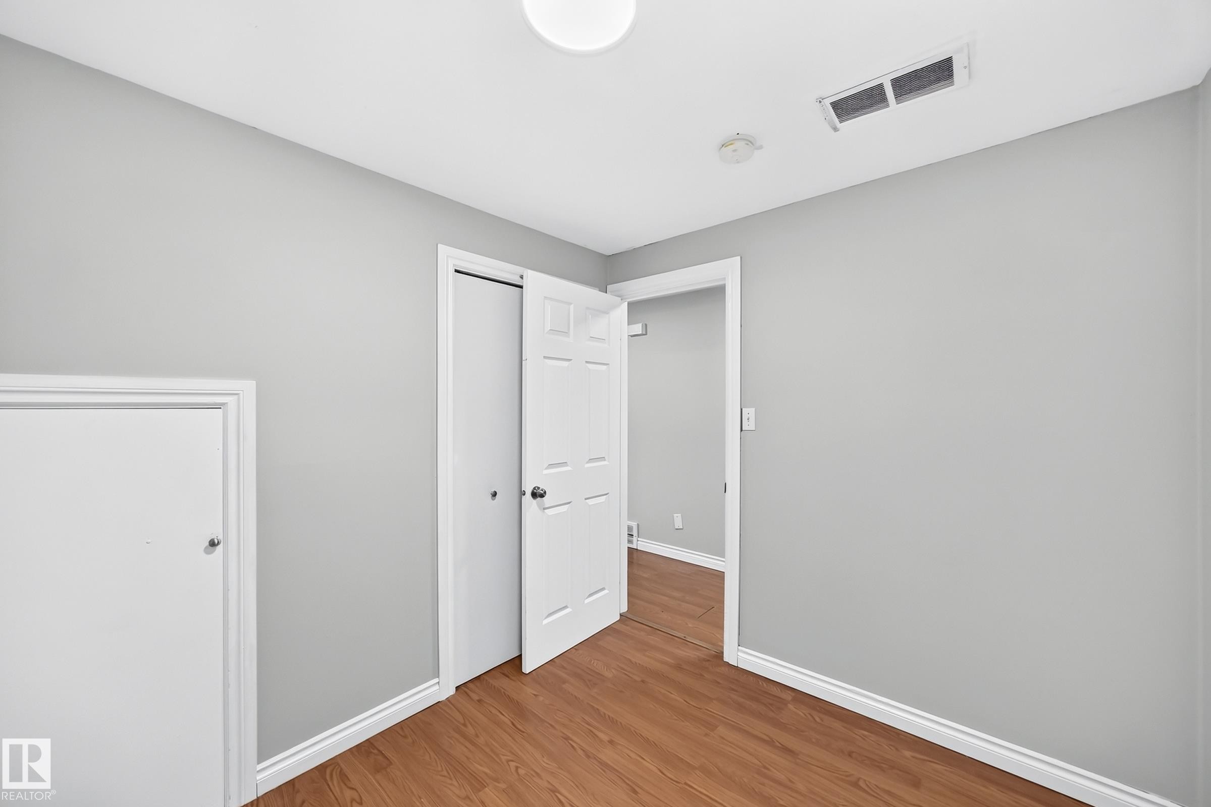 Interior room featuring wood-finish flooring, light gray wall paint, and white trim - 1103 56 Street, Edmonton, AB