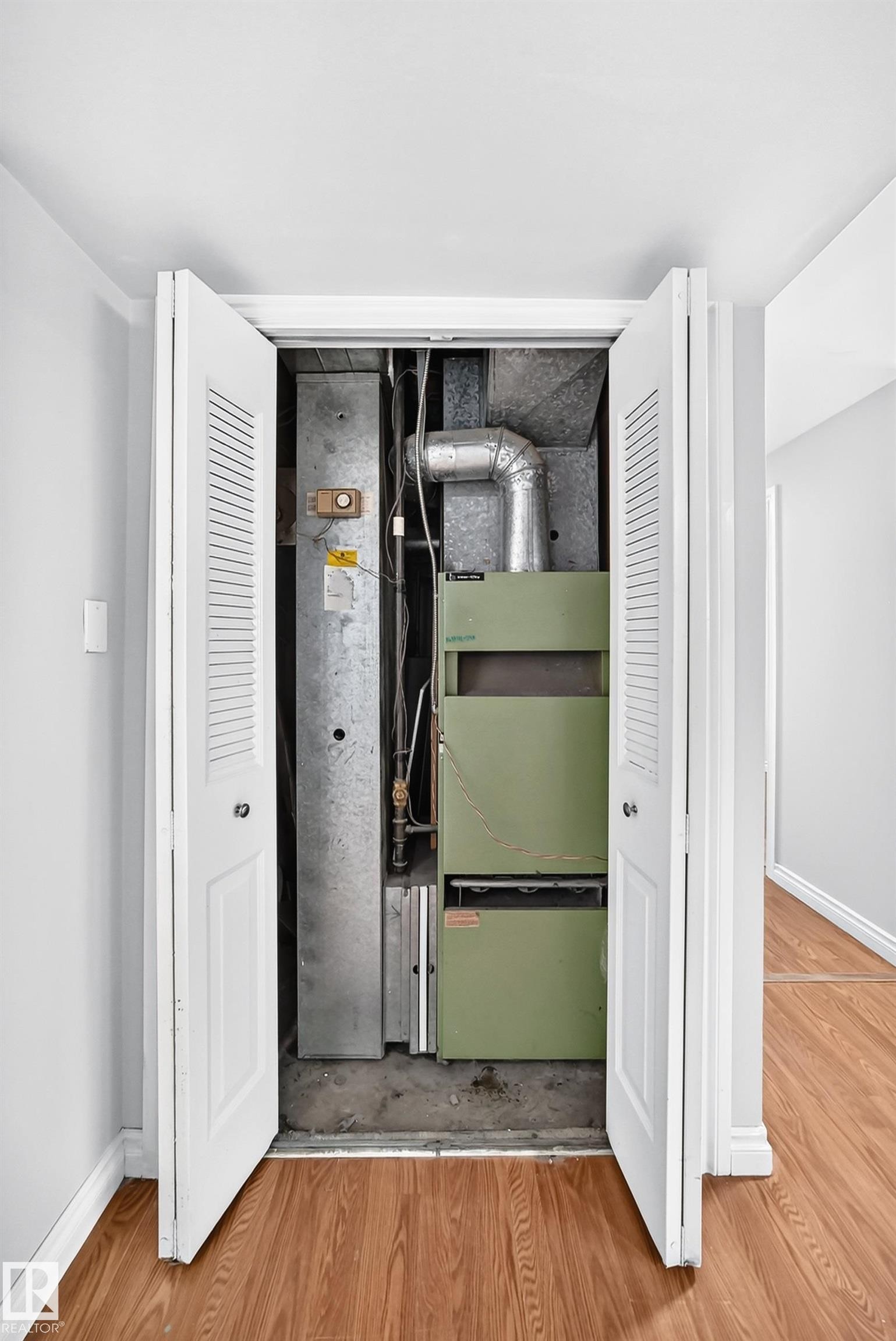 Utility closet with bi-fold louvered doors, housing a central HVAC system and ductwork - 1103 56 Street, Edmonton, AB