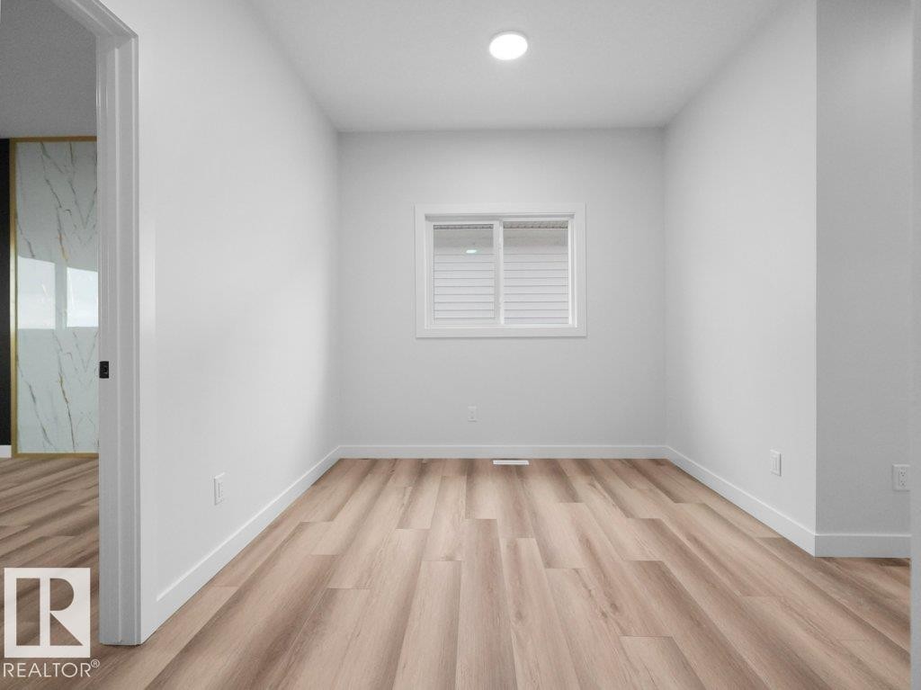 Room featuring wood-finish flooring, crisp white walls, and a recessed ceiling light - 18719 130 Street Nw, Edmonton, AB