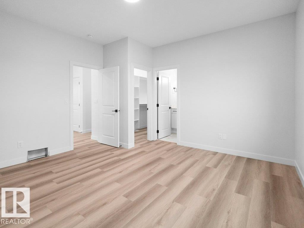 Light wood-finish flooring complements white walls and trim - 18719 130 Street Nw, Edmonton, AB