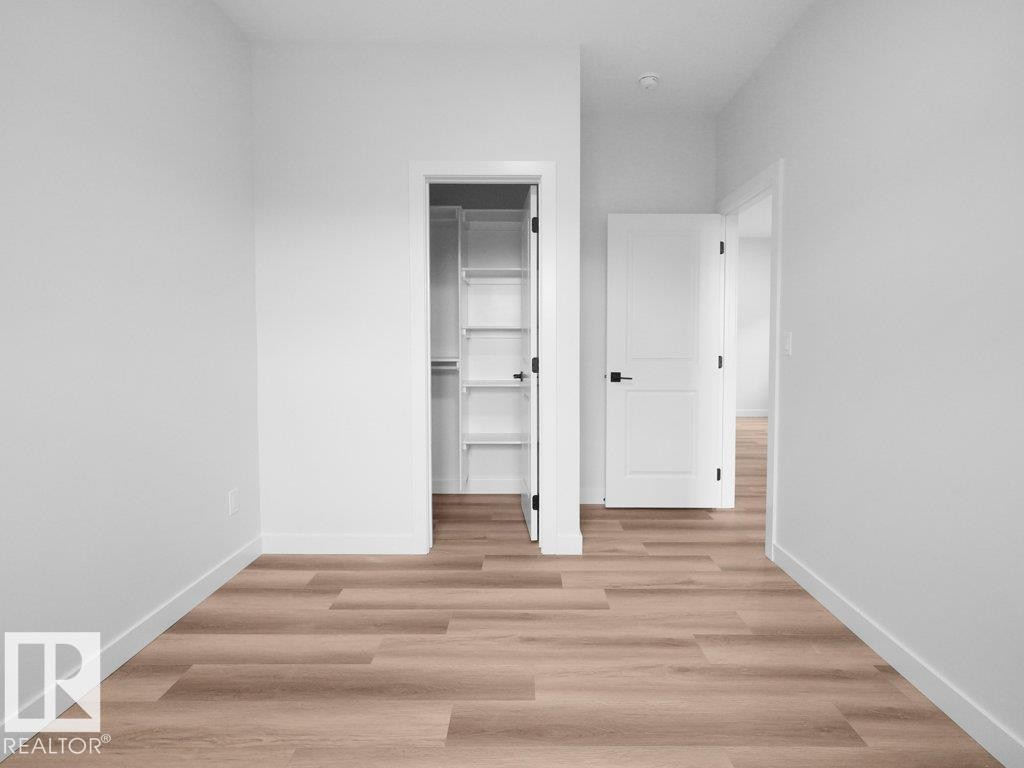 Room featuring wood-finish flooring, white walls, and bright white trim - 18719 130 Street Nw, Edmonton, AB