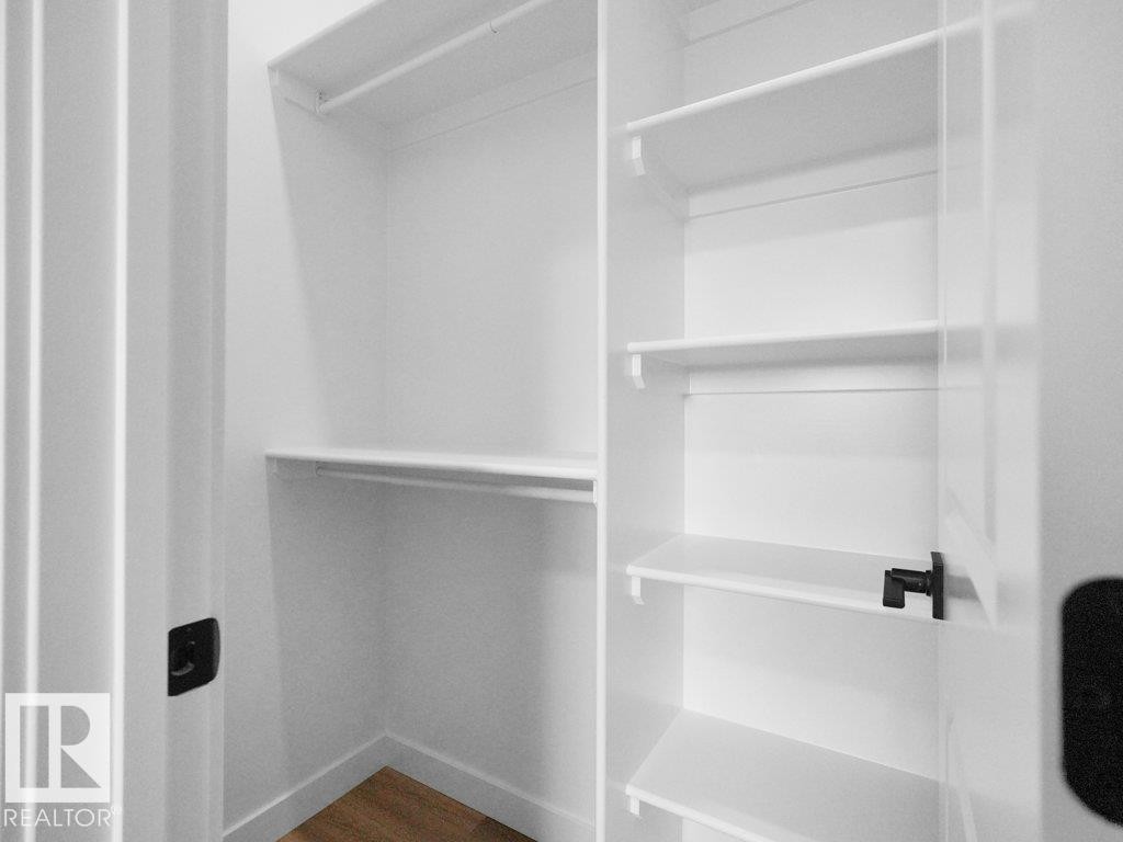Custom closet system featuring white shelving, hanging rods, and a wood-finish floor - 18719 130 Street Nw, Edmonton, AB
