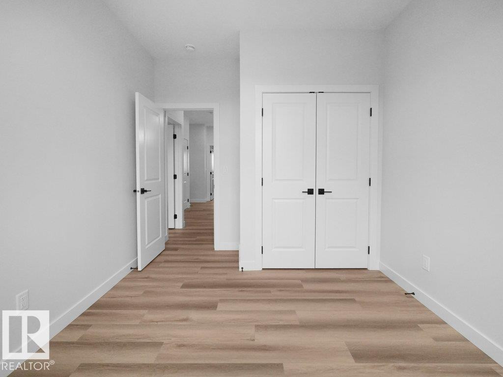 Room featuring wood-finish flooring and white baseboards - 18719 130 Street Nw, Edmonton, AB