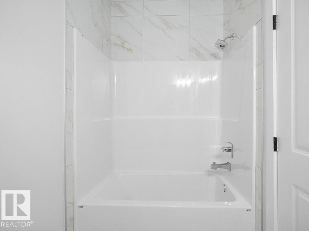 Bathtub and shower combination featuring a white surround and chrome fixtures - 18719 130 Street Nw, Edmonton, AB