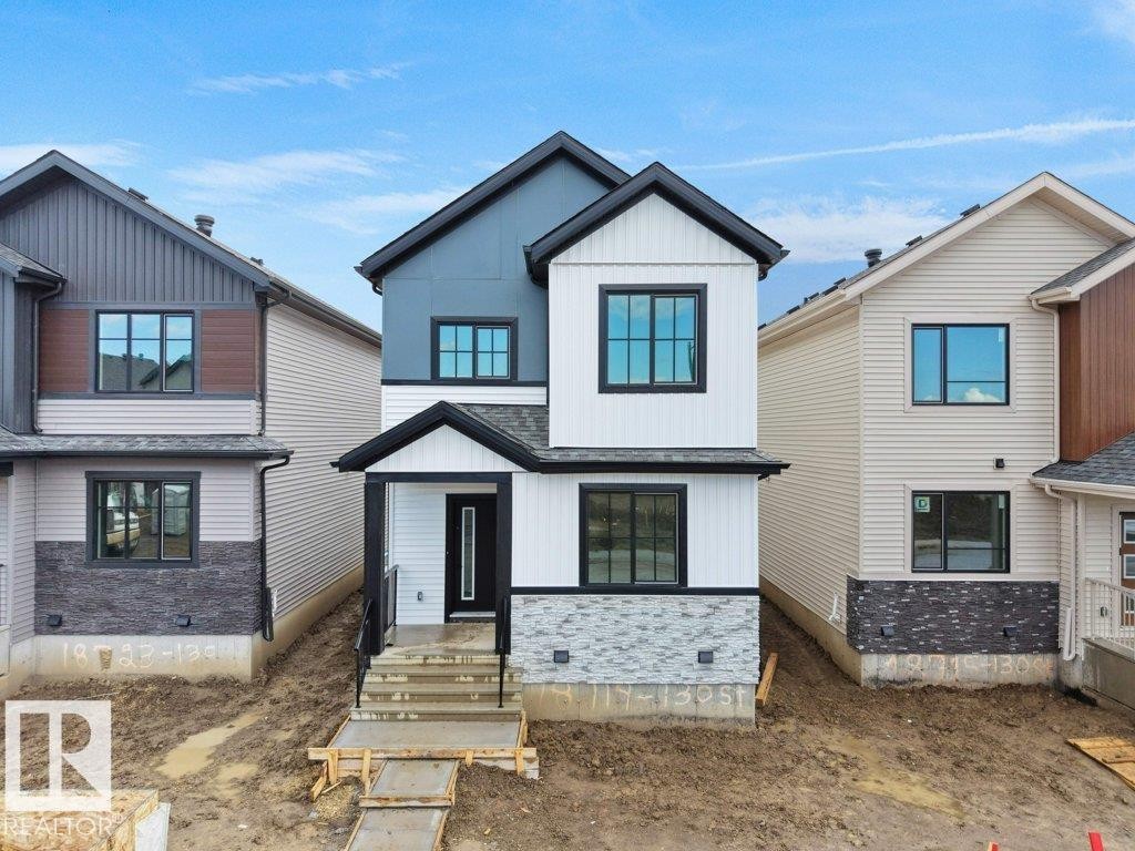 Modern facade featuring white vertical siding, dark gray horizontal siding, and a partial stone veneer base - 18719 130 Street Nw, Edmonton, AB