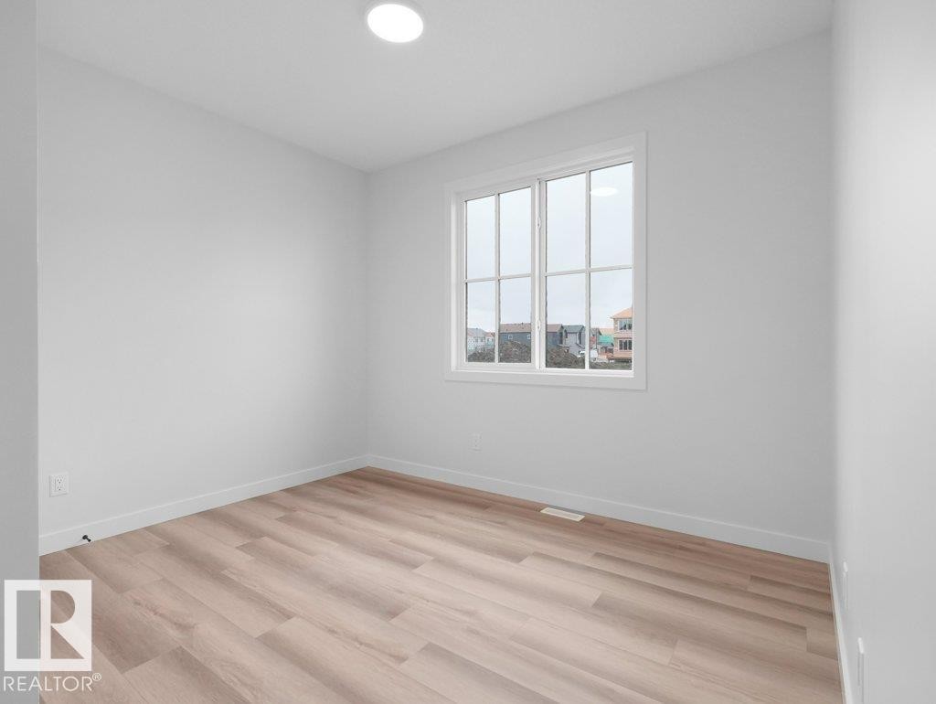 Bright interior space featuring a multi-pane window, recessed ceiling lighting, light wood-finish flooring, white baseboards, and neutral wall tones - 18719 130 Street Nw, Edmonton, AB
