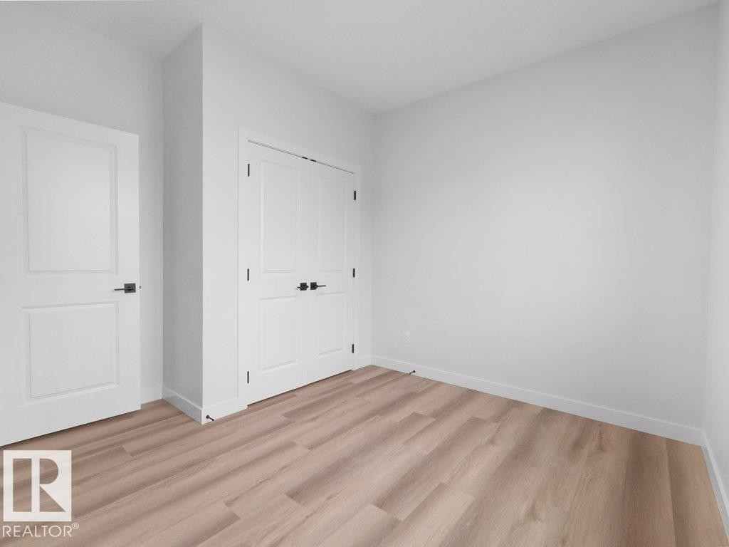 Room featuring light wood-finish flooring, white baseboards, and crisp white walls - 18719 130 Street Nw, Edmonton, AB