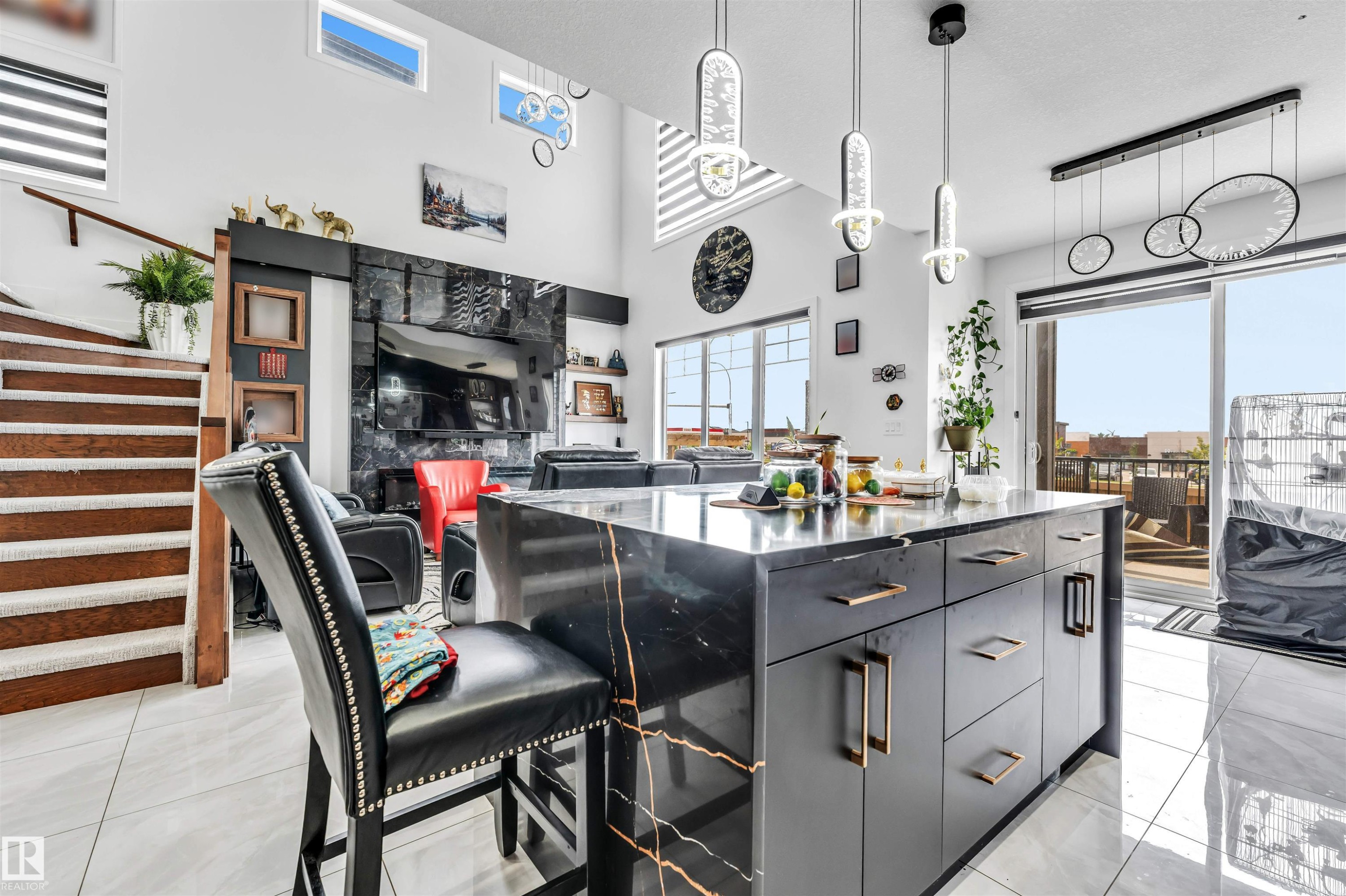 Modern kitchen island with a black and gold veined countertop, dark cabinetry, and contemporary pendant lighting - 208 33 Street, Edmonton, AB
