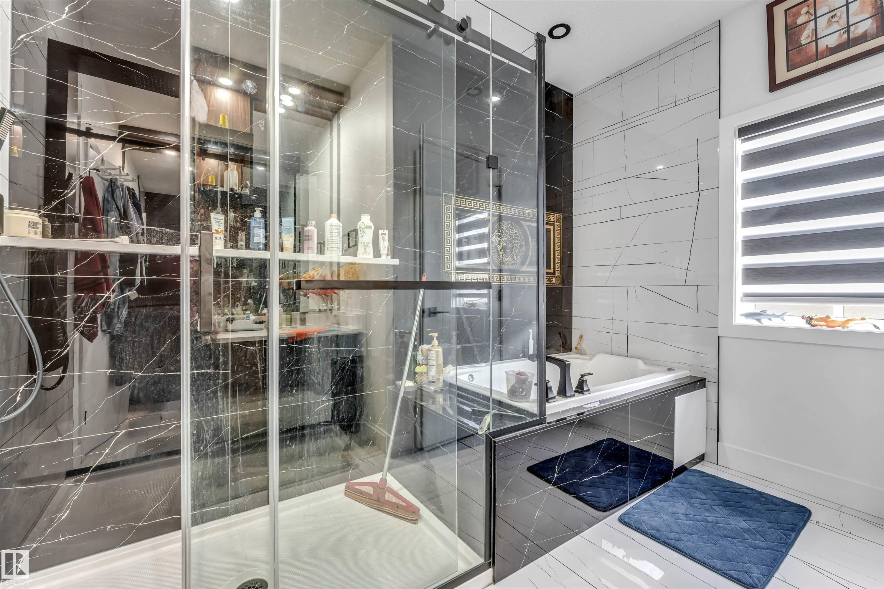 Contemporary bathroom featuring a walk-in shower with clear glass enclosure, black marbled wall tiling, a built-in soaking tub, and contrasting white wall tiling - 208 33 Street, Edmonton, AB