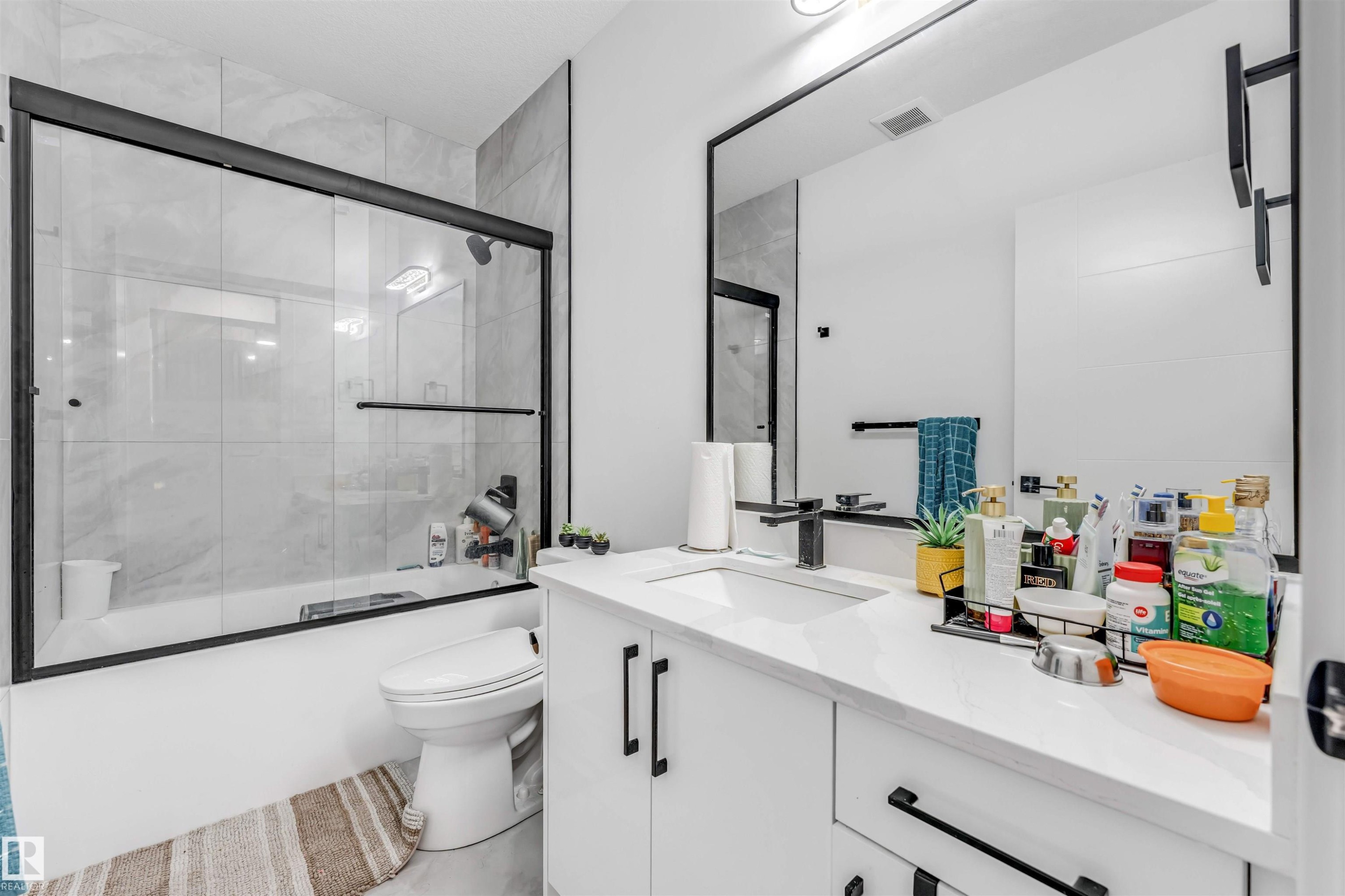 Bathroom featuring a modern vanity with white countertop, integrated sink, and matte black faucet - 208 33 Street, Edmonton, AB