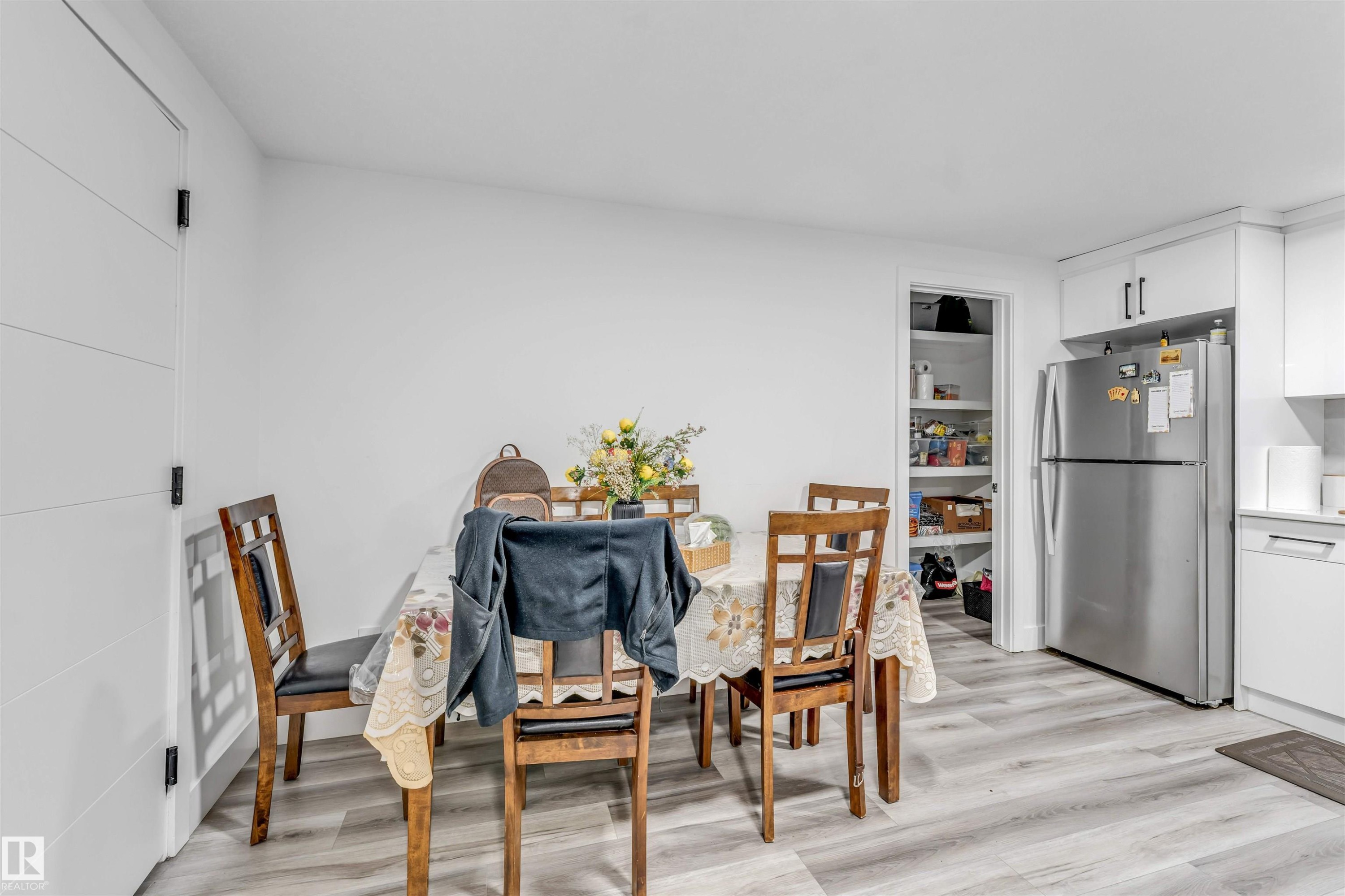 Bright dining area featuring wood-finish flooring and a contemporary white door with horizontal paneling - 208 33 Street, Edmonton, AB
