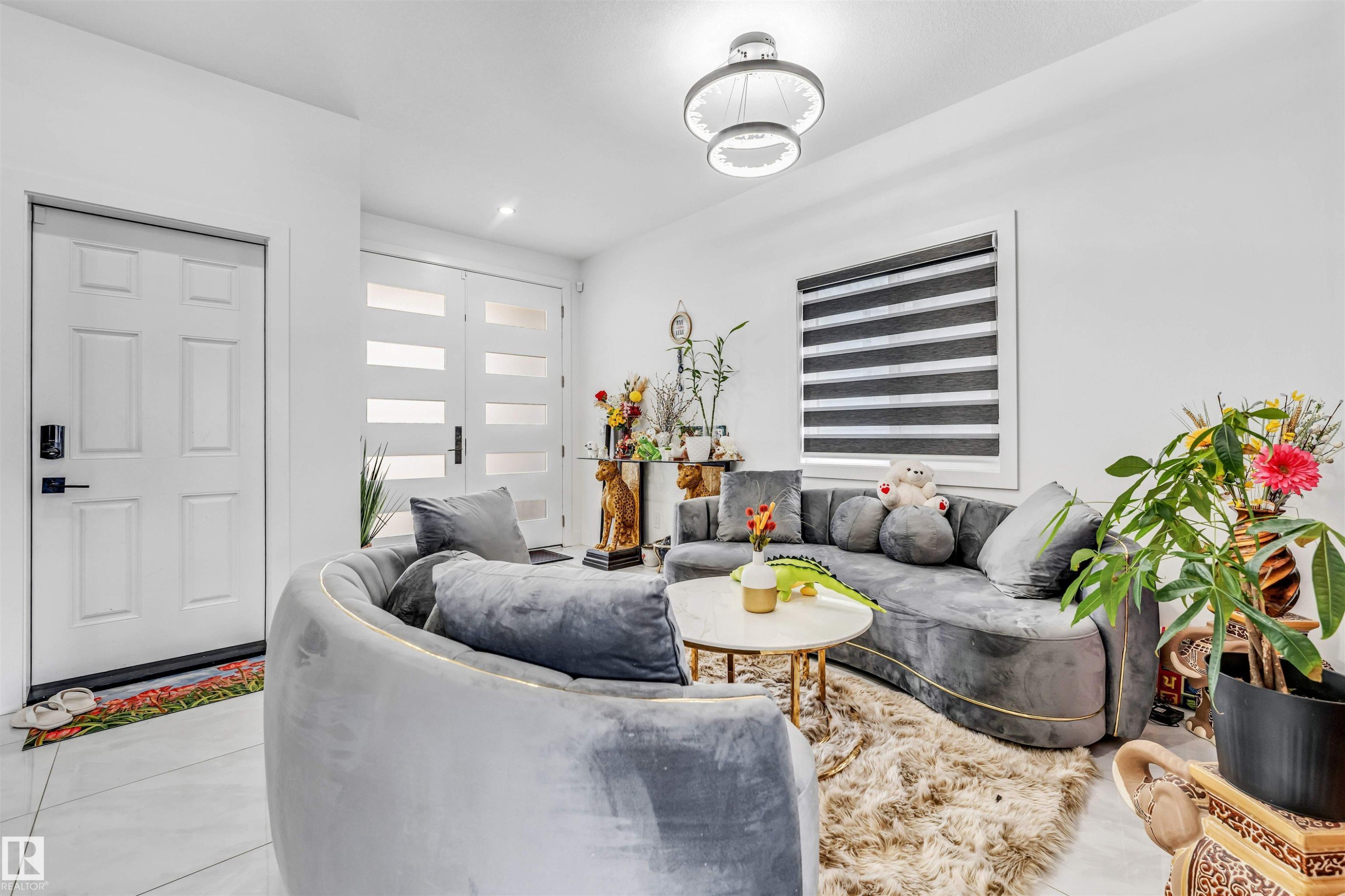 Bright entry space featuring white paneled doors, modern frosted glass double doors, a contemporary ceiling light fixture, and tile flooring - 208 33 Street, Edmonton, AB