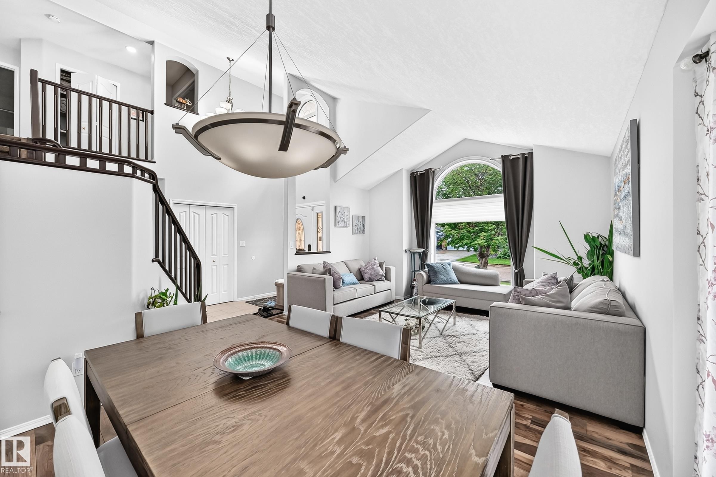 Spacious living area featuring a vaulted ceiling and a prominent staircase with dark wood-finish railing - 4216 47 Street, Edmonton, AB