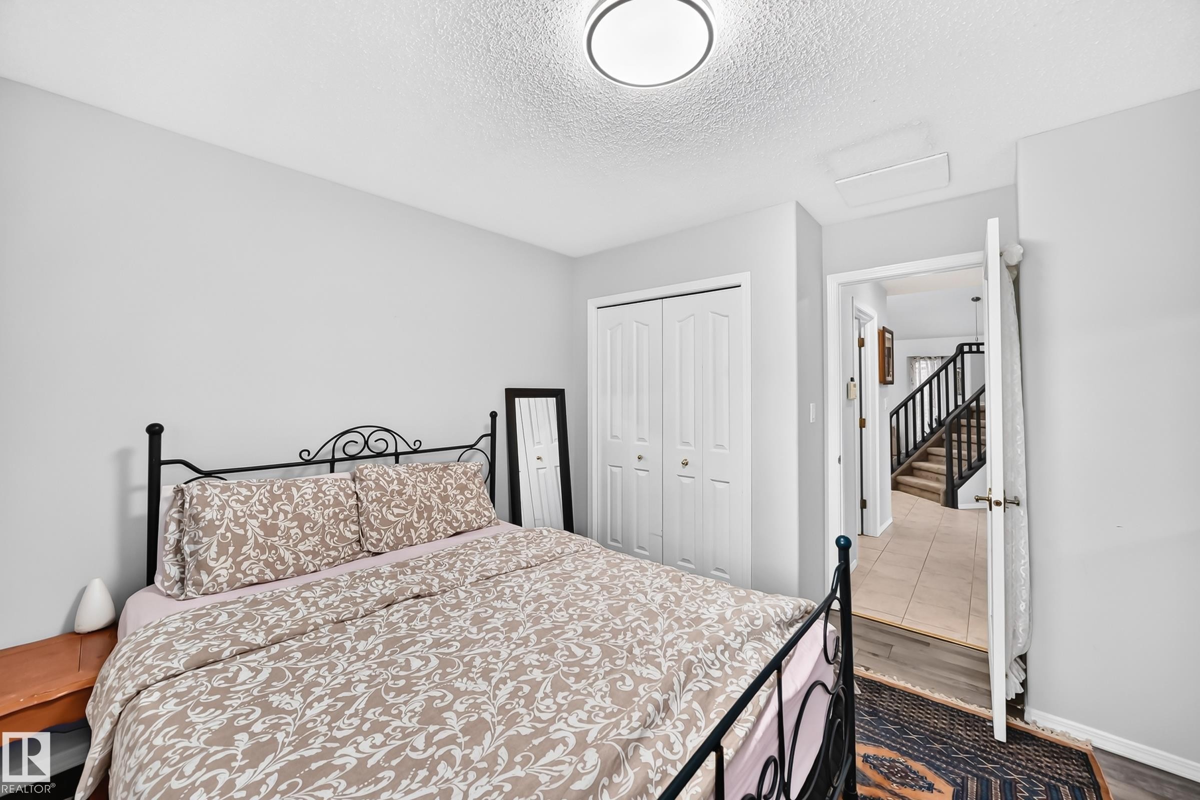 Bedroom featuring light gray walls, wood-finish flooring, and a flush-mount ceiling light - 4216 47 Street, Edmonton, AB