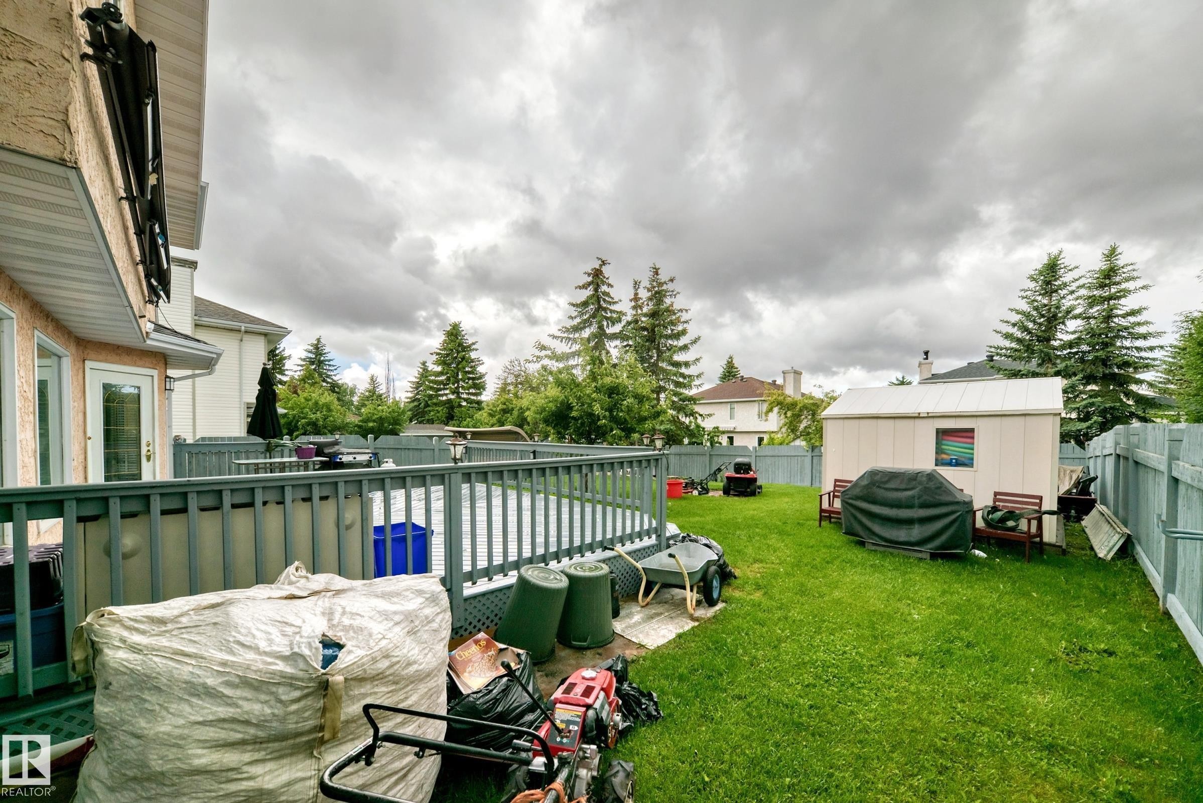 Expansive rear yard featuring an above-ground pool with surrounding deck and railing, a detached storage shed, and mature perimeter trees - 4216 47 Street, Edmonton, AB