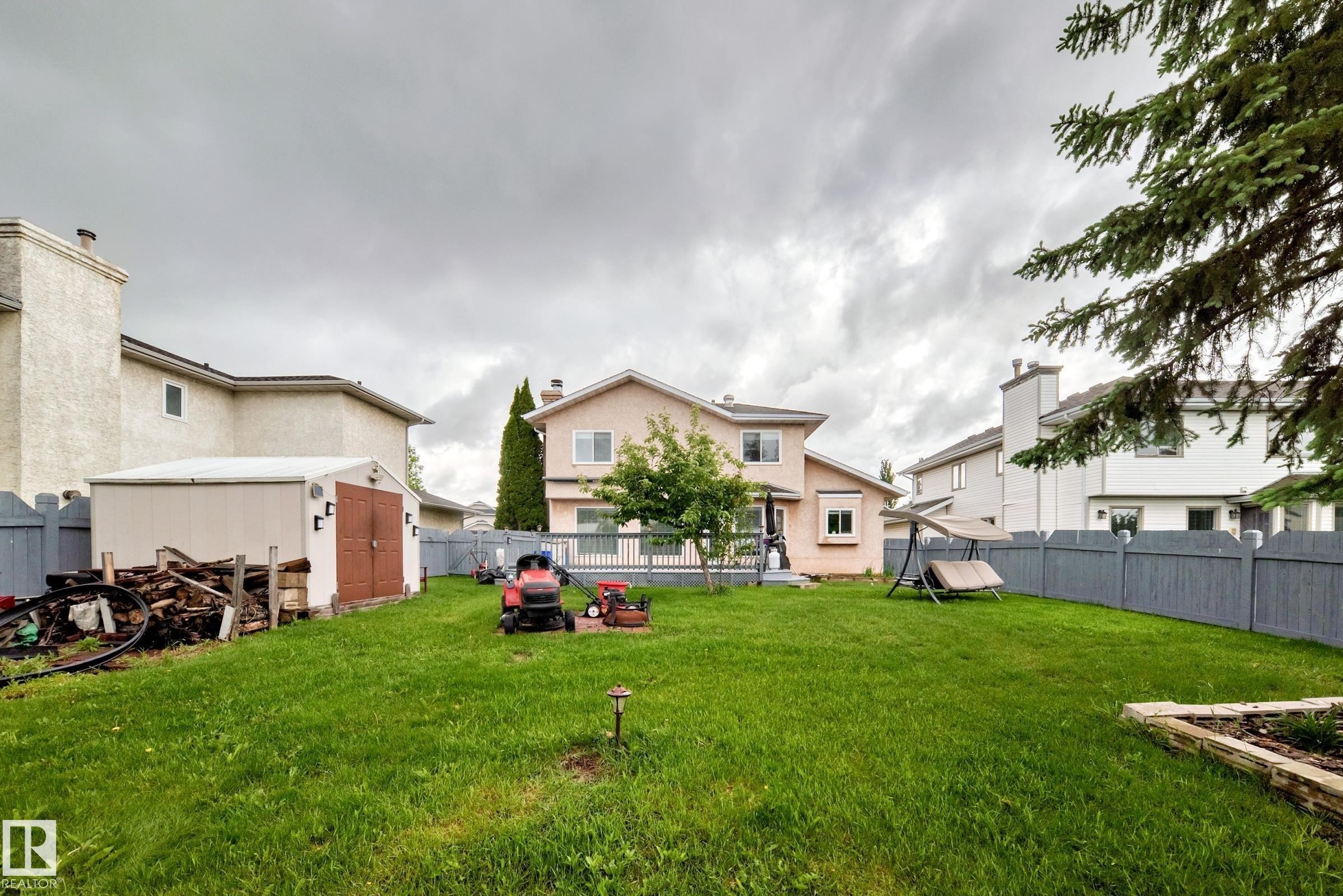 Expansive backyard featuring a manicured lawn, a privacy fence, and a storage shed with double doors - 4216 47 Street, Edmonton, AB