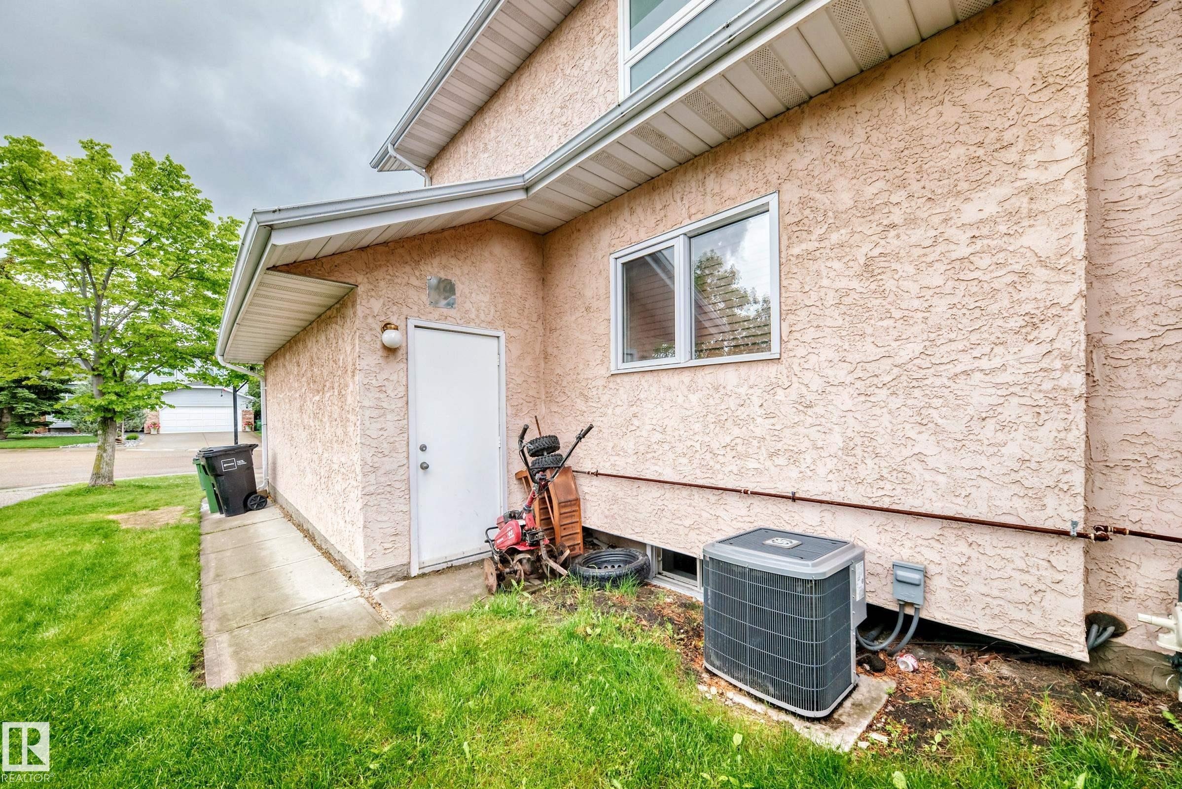 Stucco exterior with white trim, featuring a side entry door and a window - 4216 47 Street, Edmonton, AB