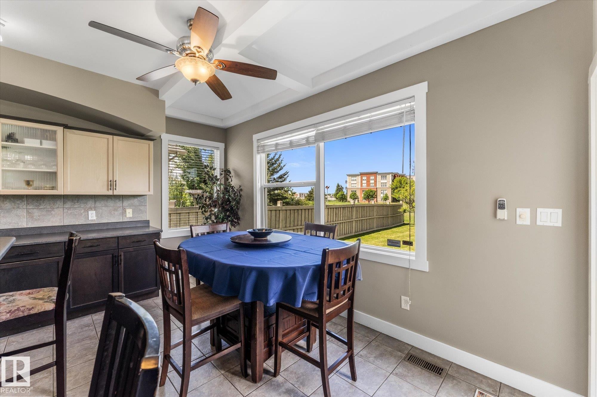 Eat-in kitchen area featuring a coffered ceiling with a ceiling fan, tiled flooring, and multiple windows - 488 Macewan Road, Edmonton, AB