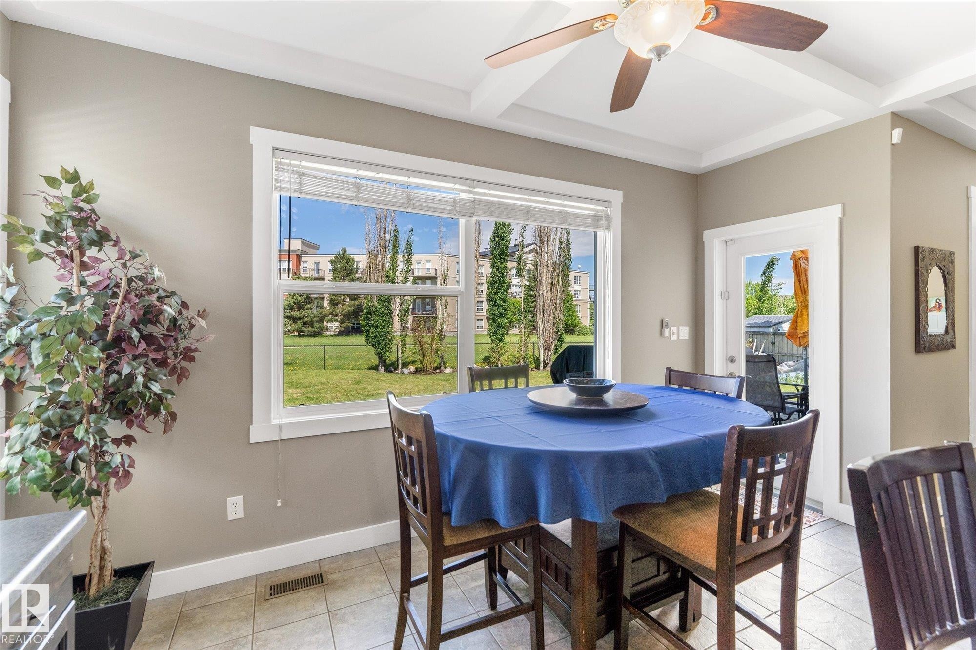 Window-lined dining area featuring tile flooring, a coffered ceiling with a ceiling fan, and white trim - 488 Macewan Road, Edmonton, AB