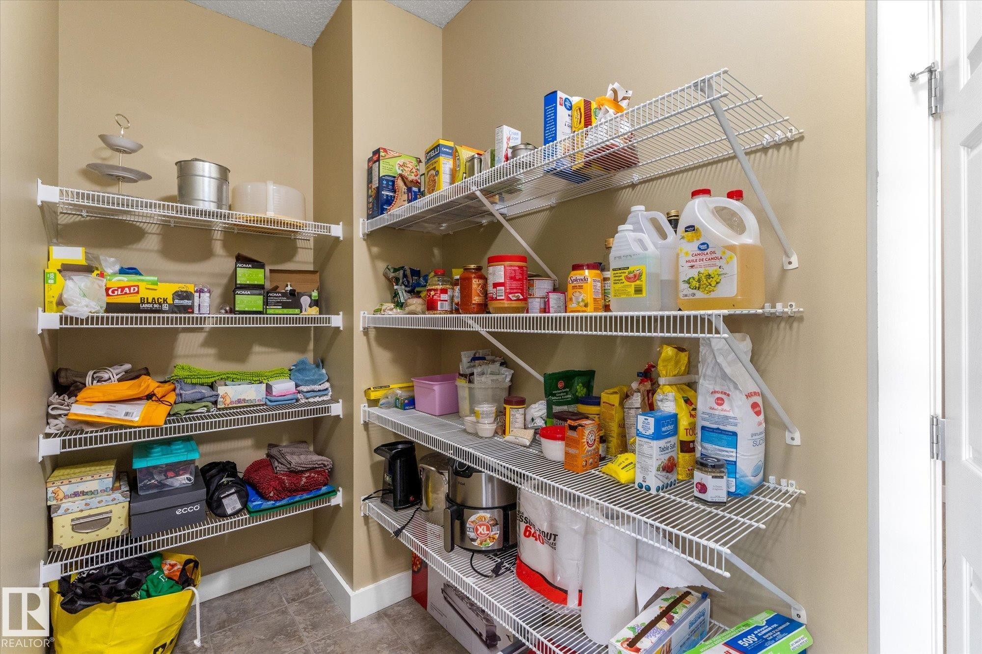 Built-in wire shelving system providing ample storage, neutral wall paint, and durable tile flooring - 488 Macewan Road, Edmonton, AB