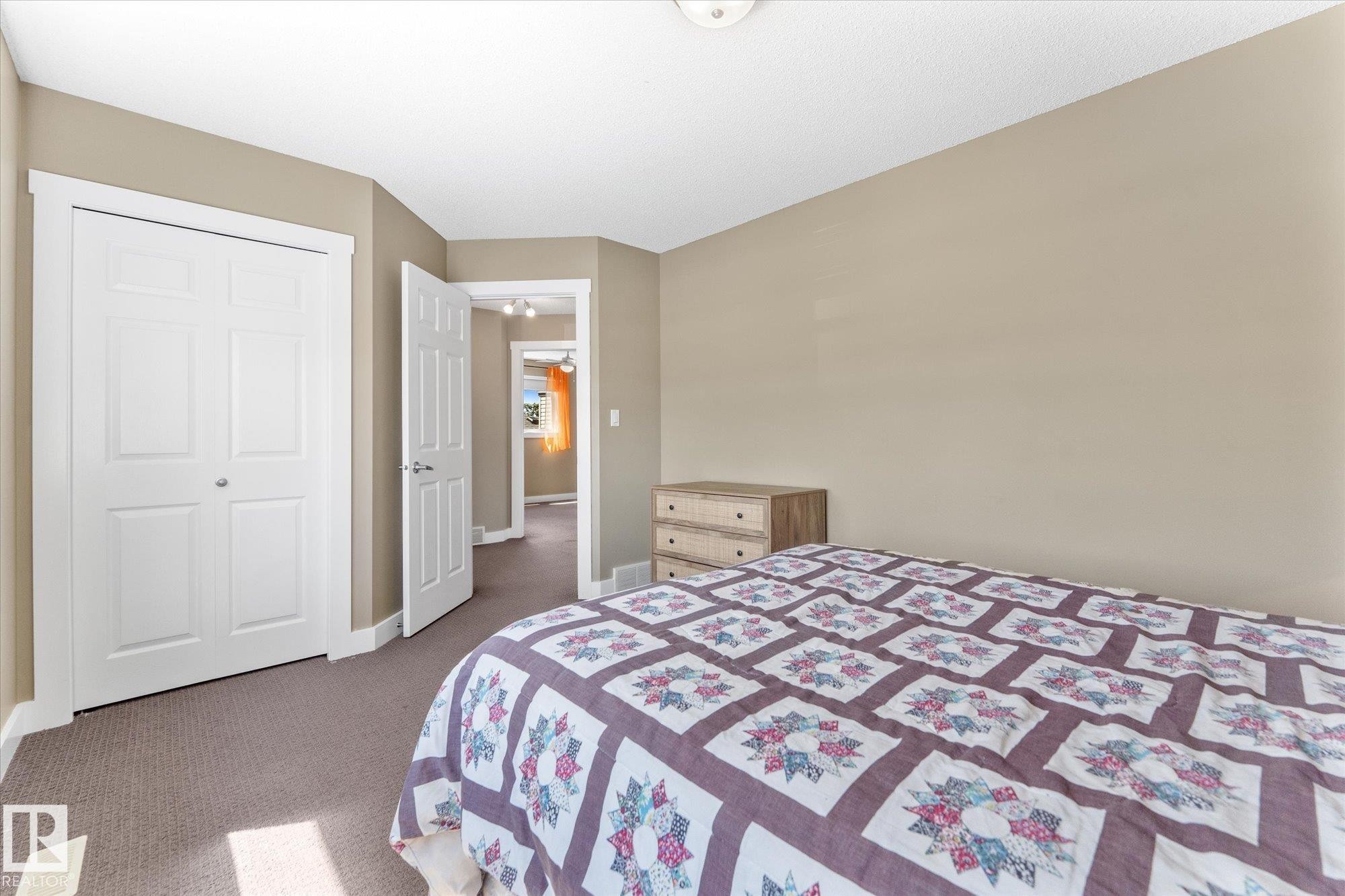 Carpeted room with a bi-fold closet, neutral wall paint, and white trim - 488 Macewan Road, Edmonton, AB